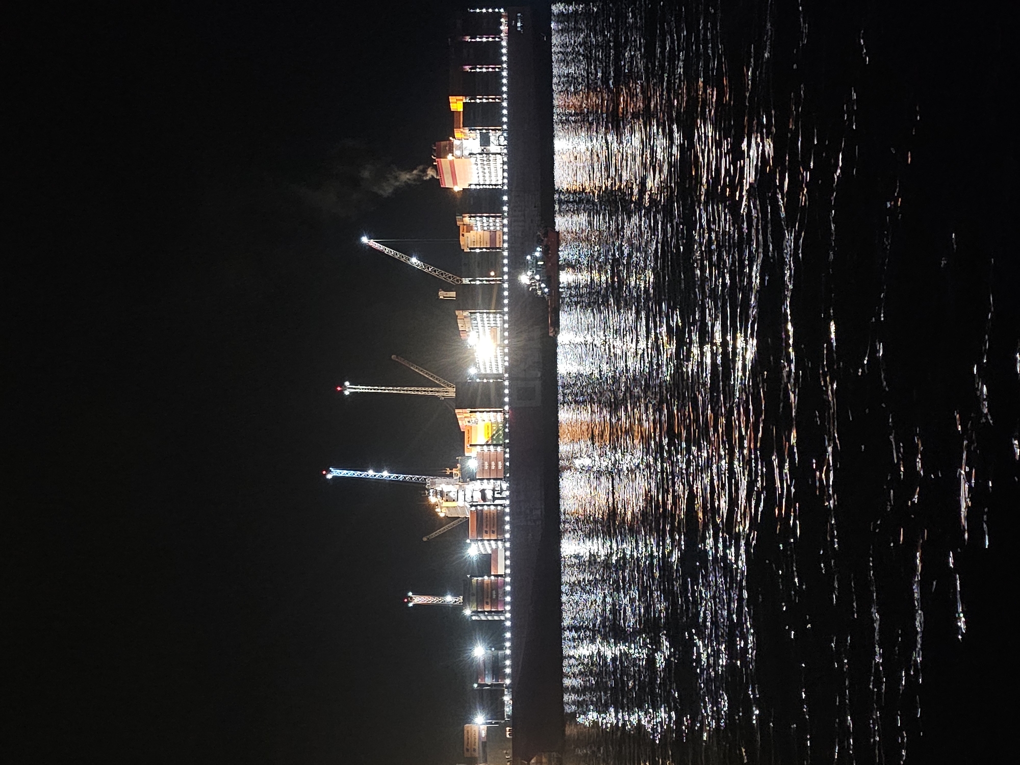 Late-night waterfront hangout with a cargo ship backdrop in Iquique