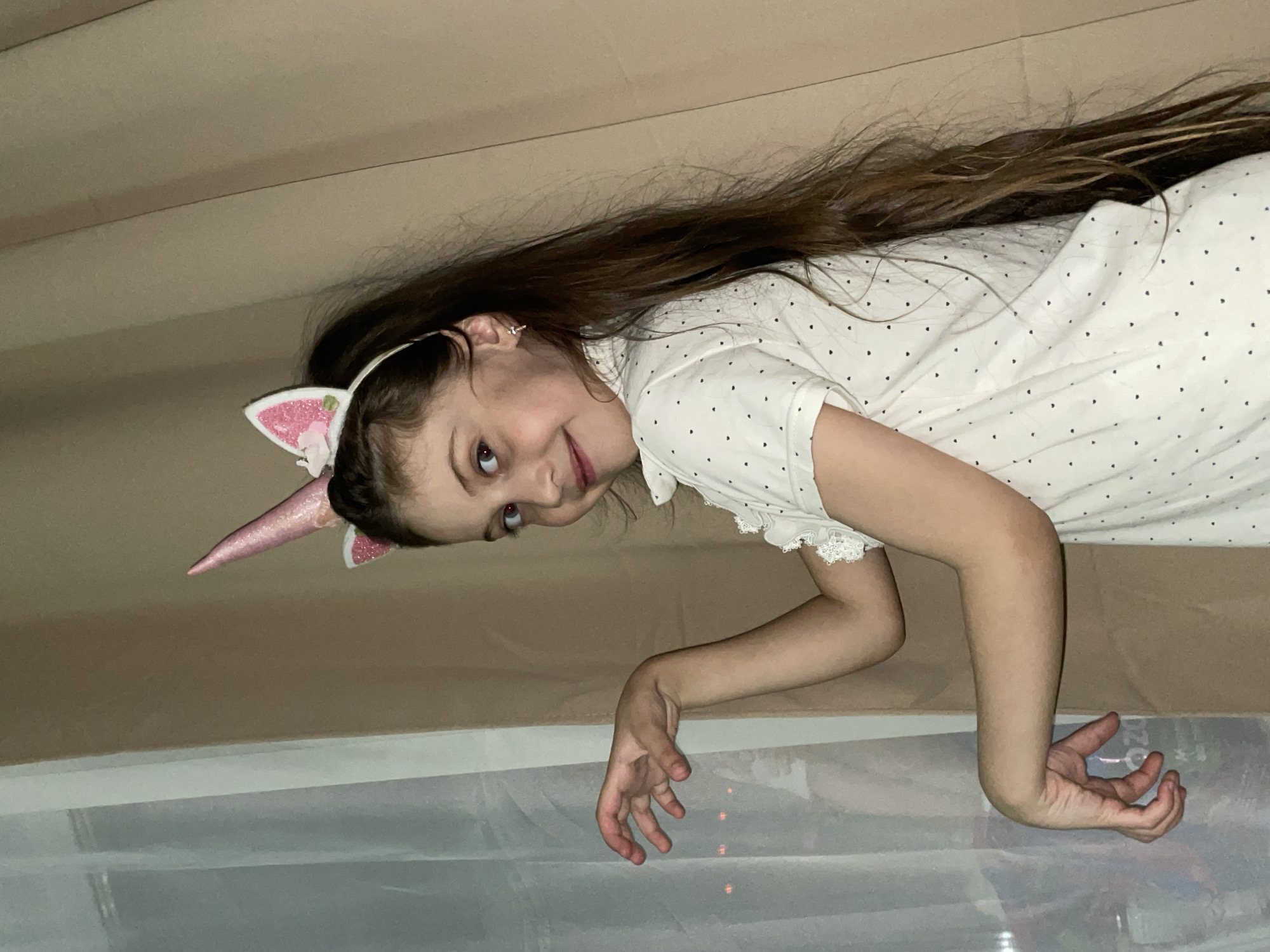 Girl in unicorn headband plays on bed in Izhevsk