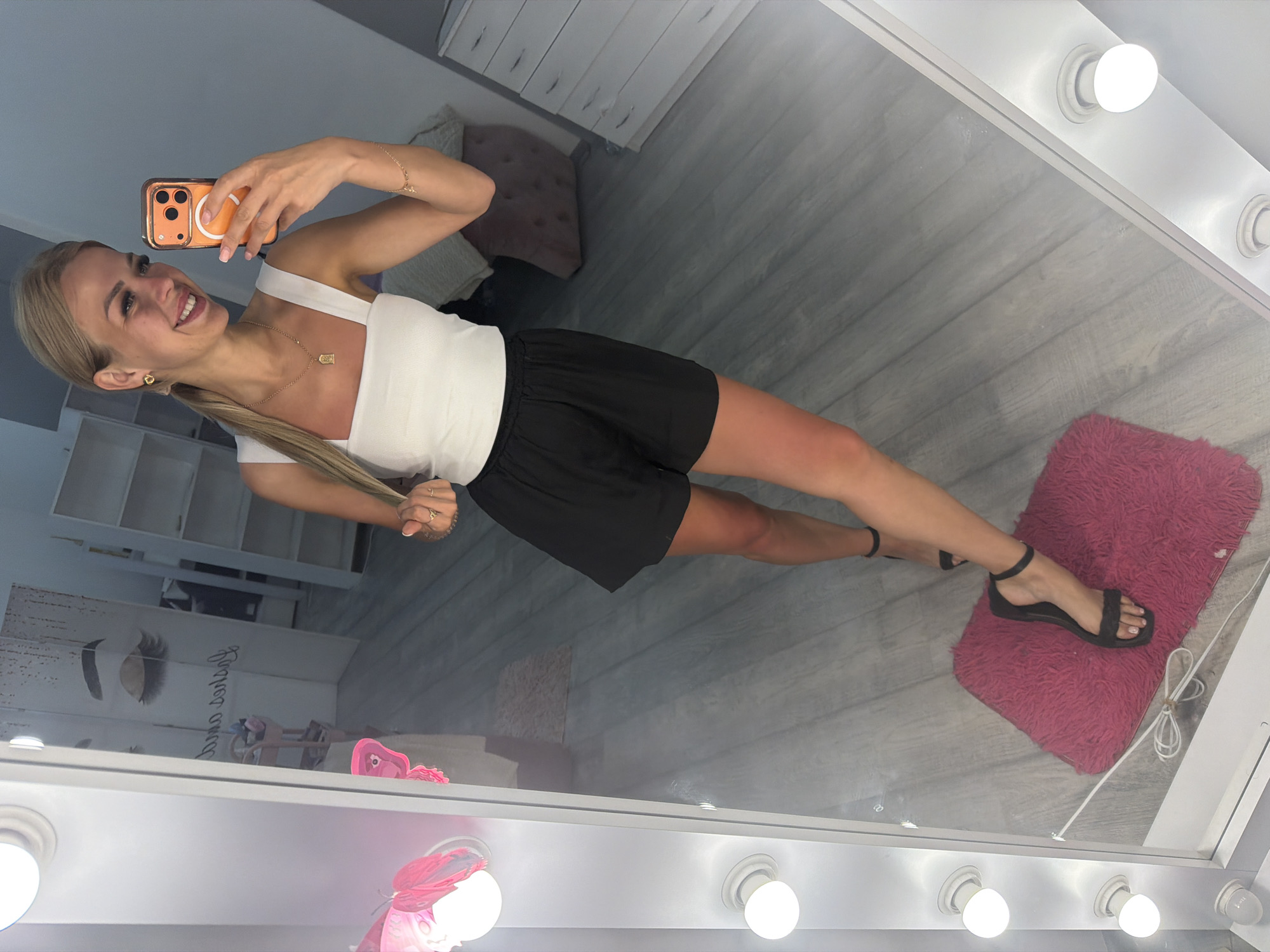Selfie moment in a salon mirror with an orange phone