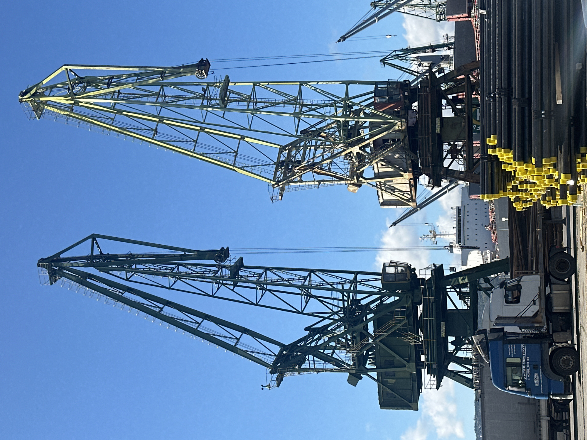 Industrial port cranes and stacked pipes on a clear day