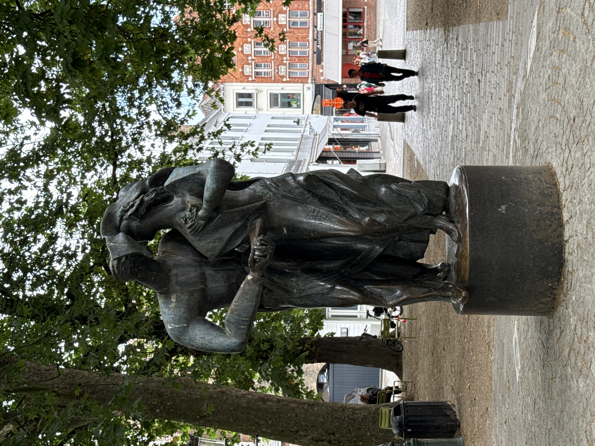 Street-level moments around a bronze sculpture in central Bruges