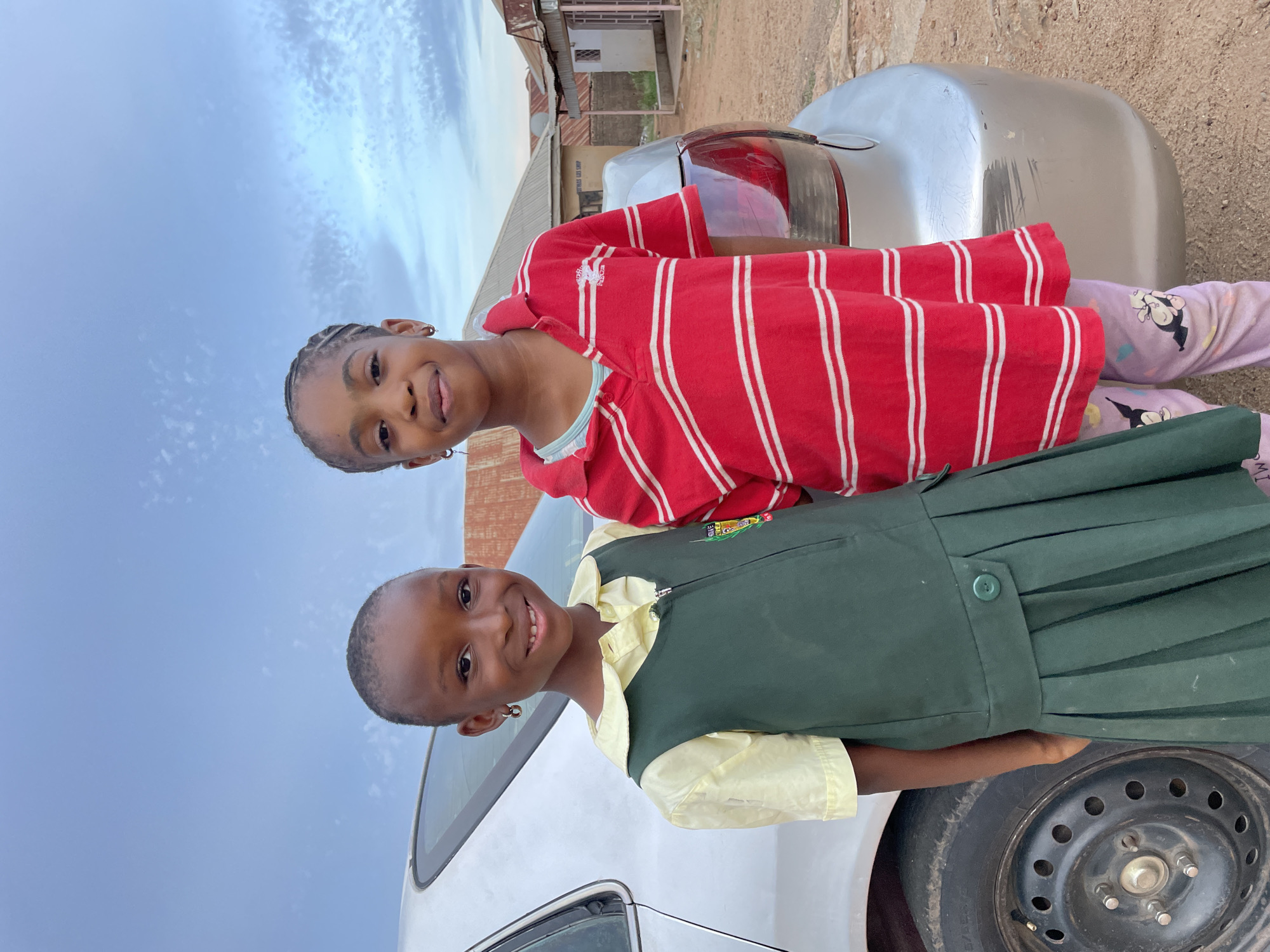 Nigerian school children pose with silver car after classes