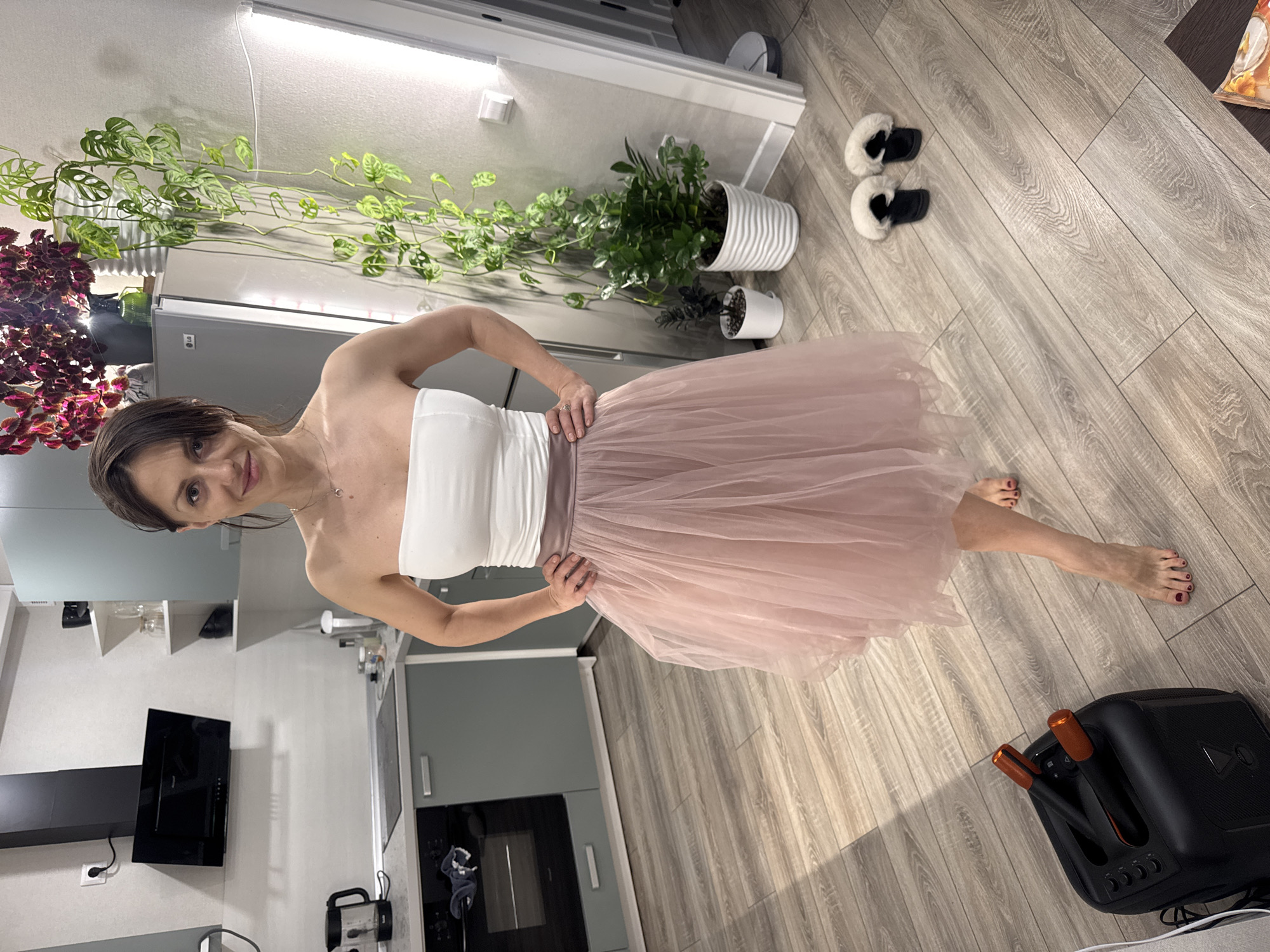 Woman twirls in pink tulle skirt in Murino apartment kitchen