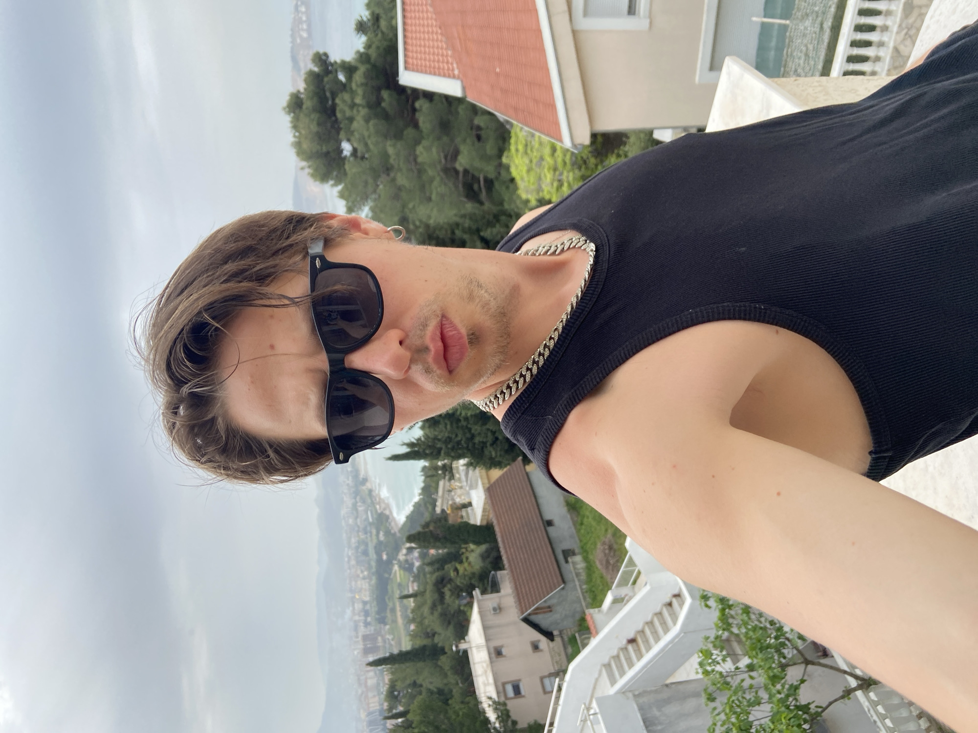 Tourist captures selfies on Montenegro balcony overlooking coastal town