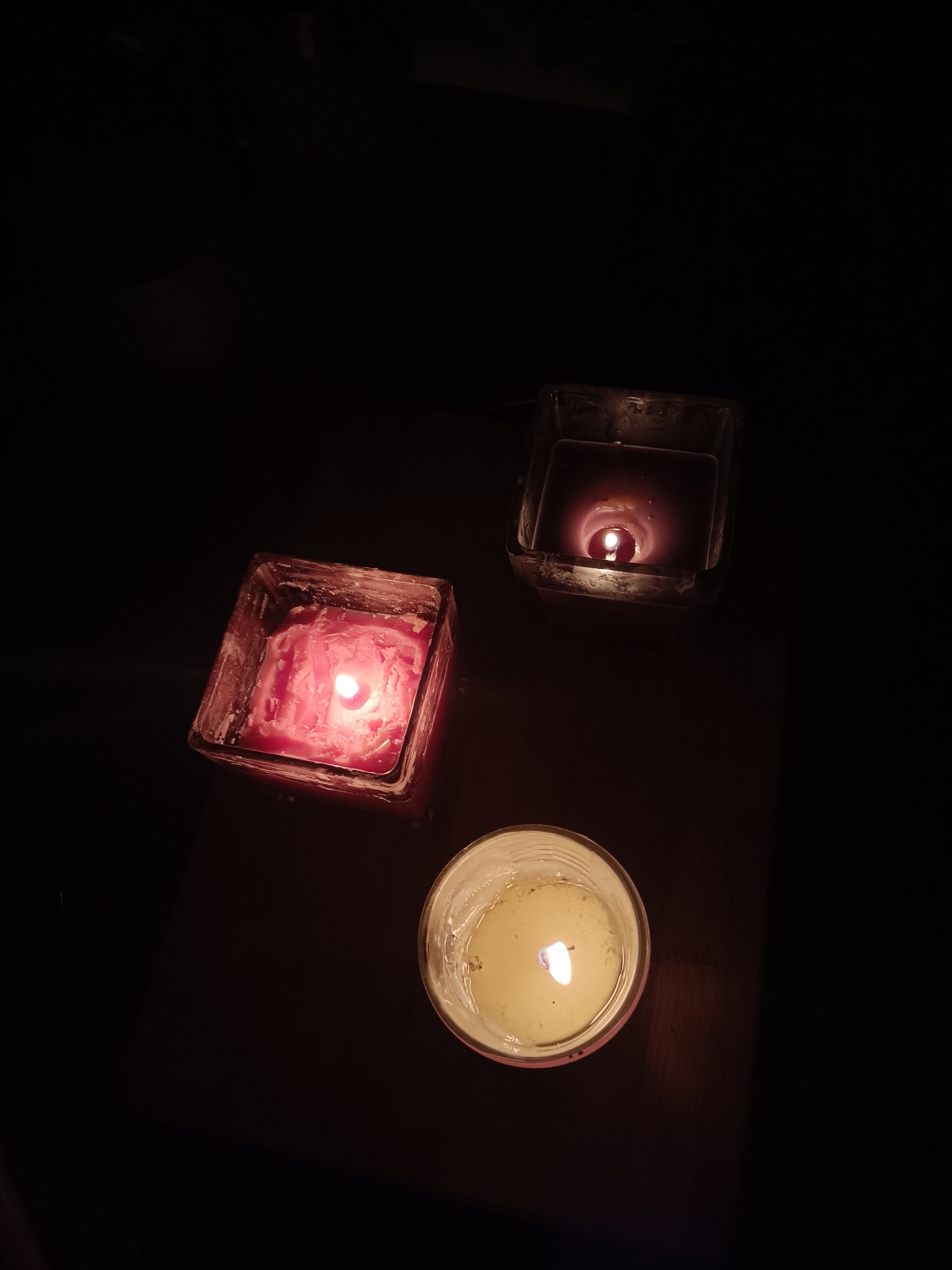 Three decorative candles lit on dark surface in Plovdiv