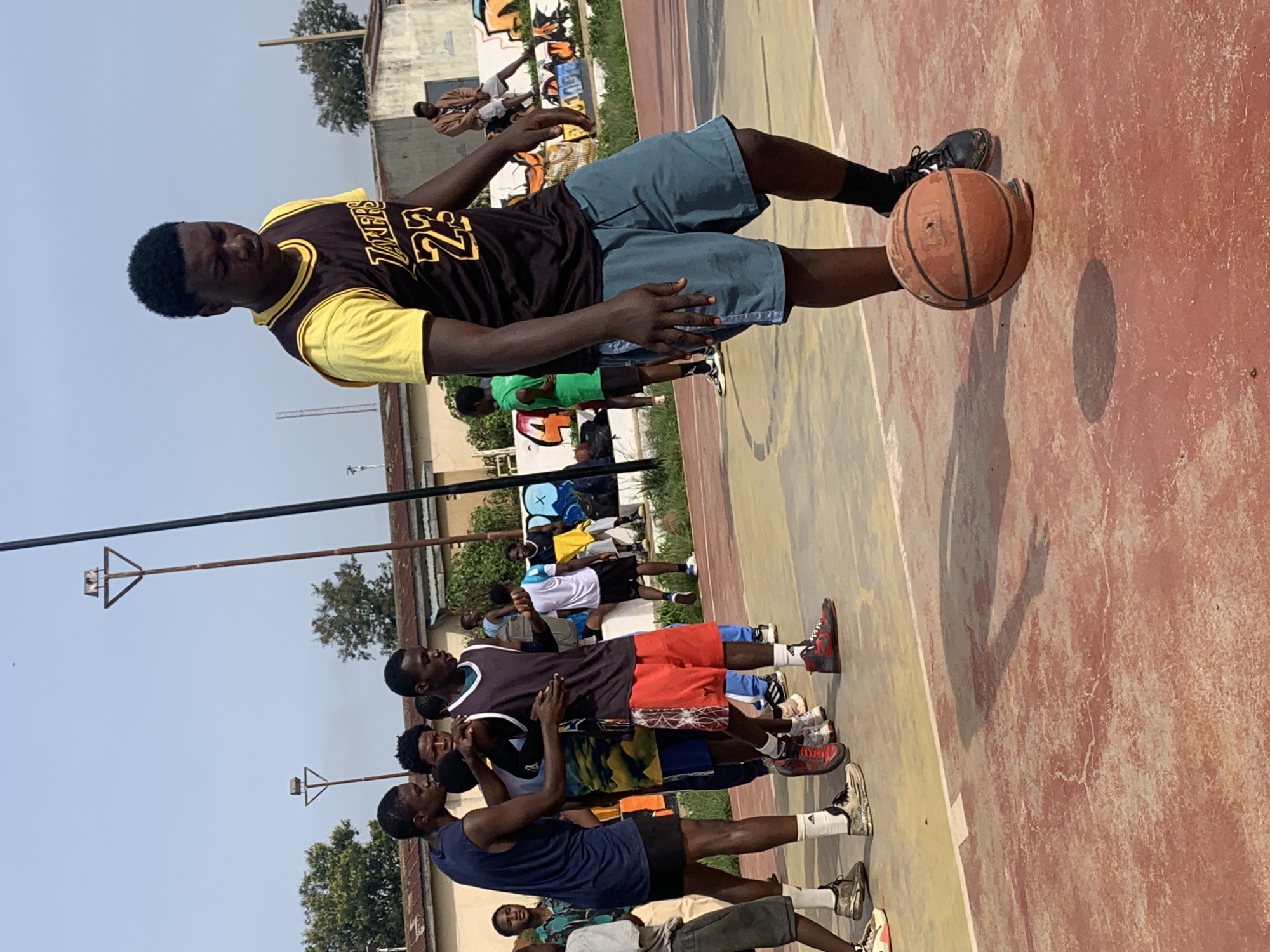 Pickup basketball on a red-and-yellow court in Gura Top, Nigeria.