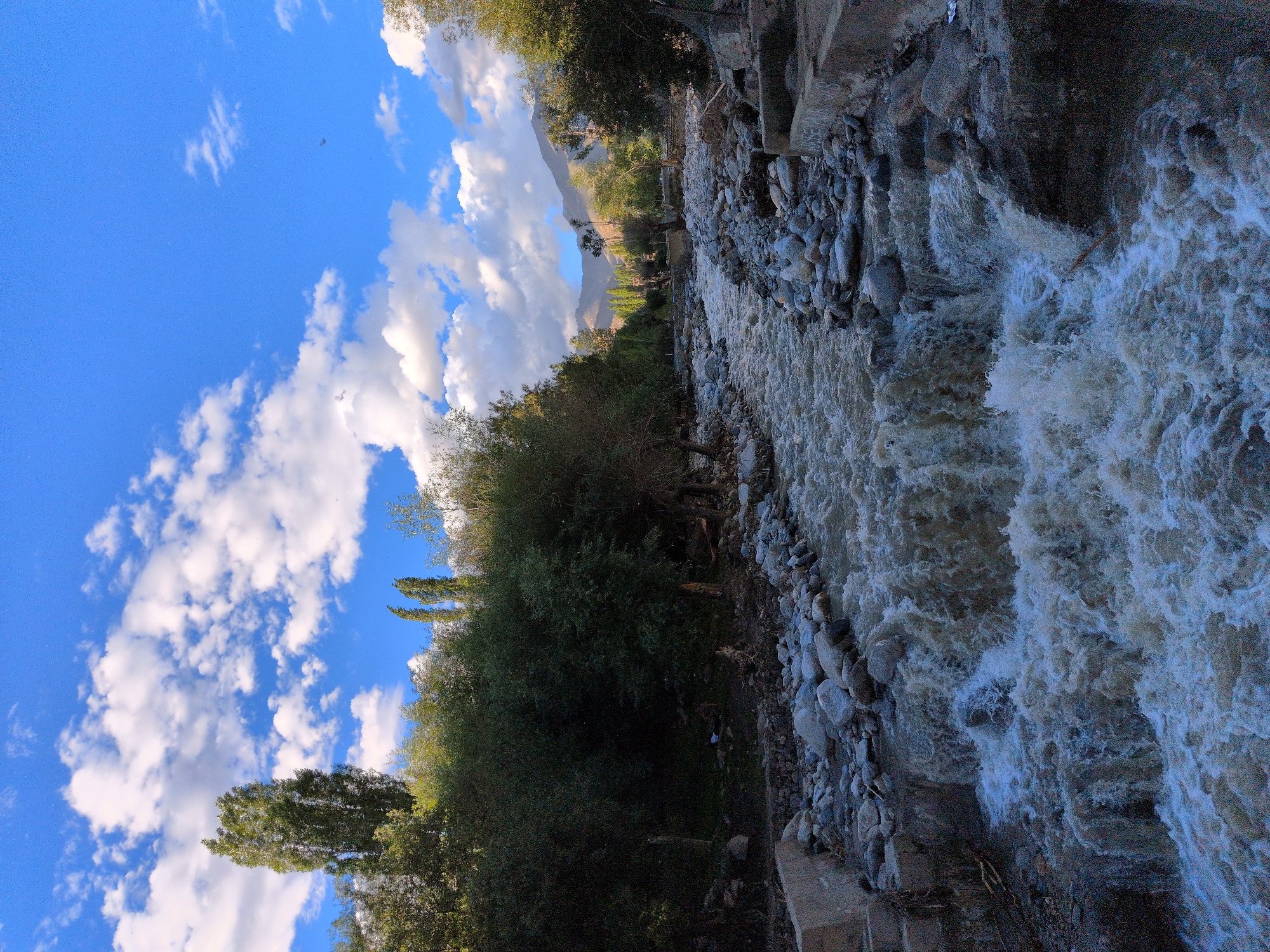 Murky river surges through rocky Leh valley on sunny afternoon