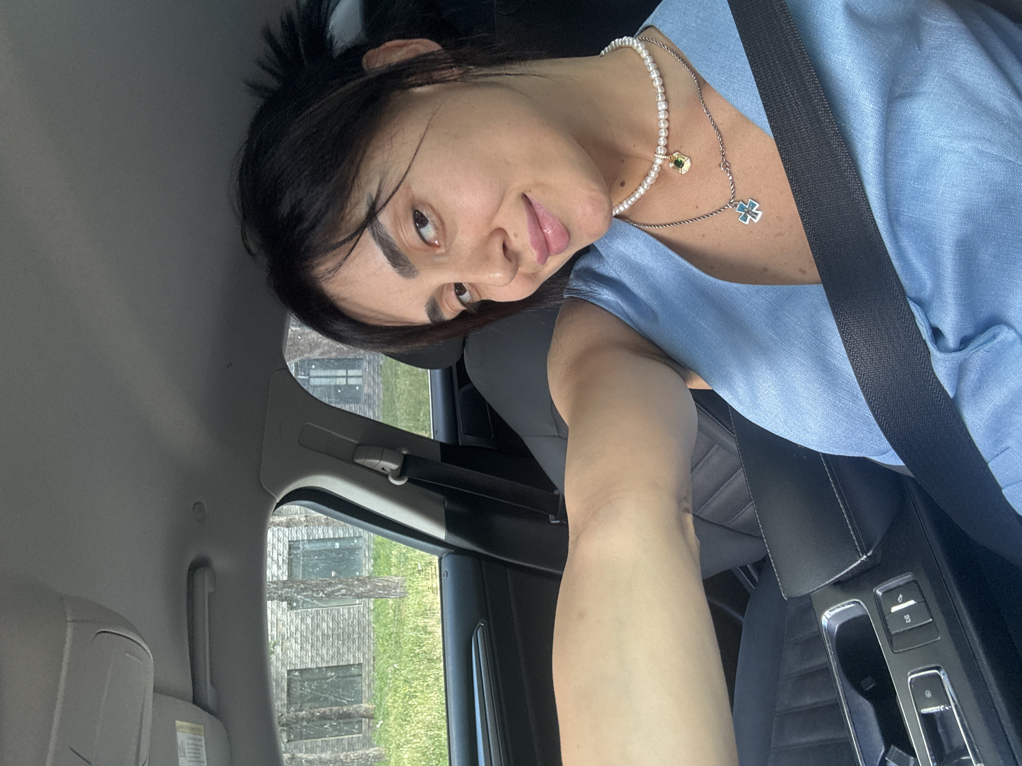 Driver selfies in Tbilisi traffic, light blue top and pearl necklace