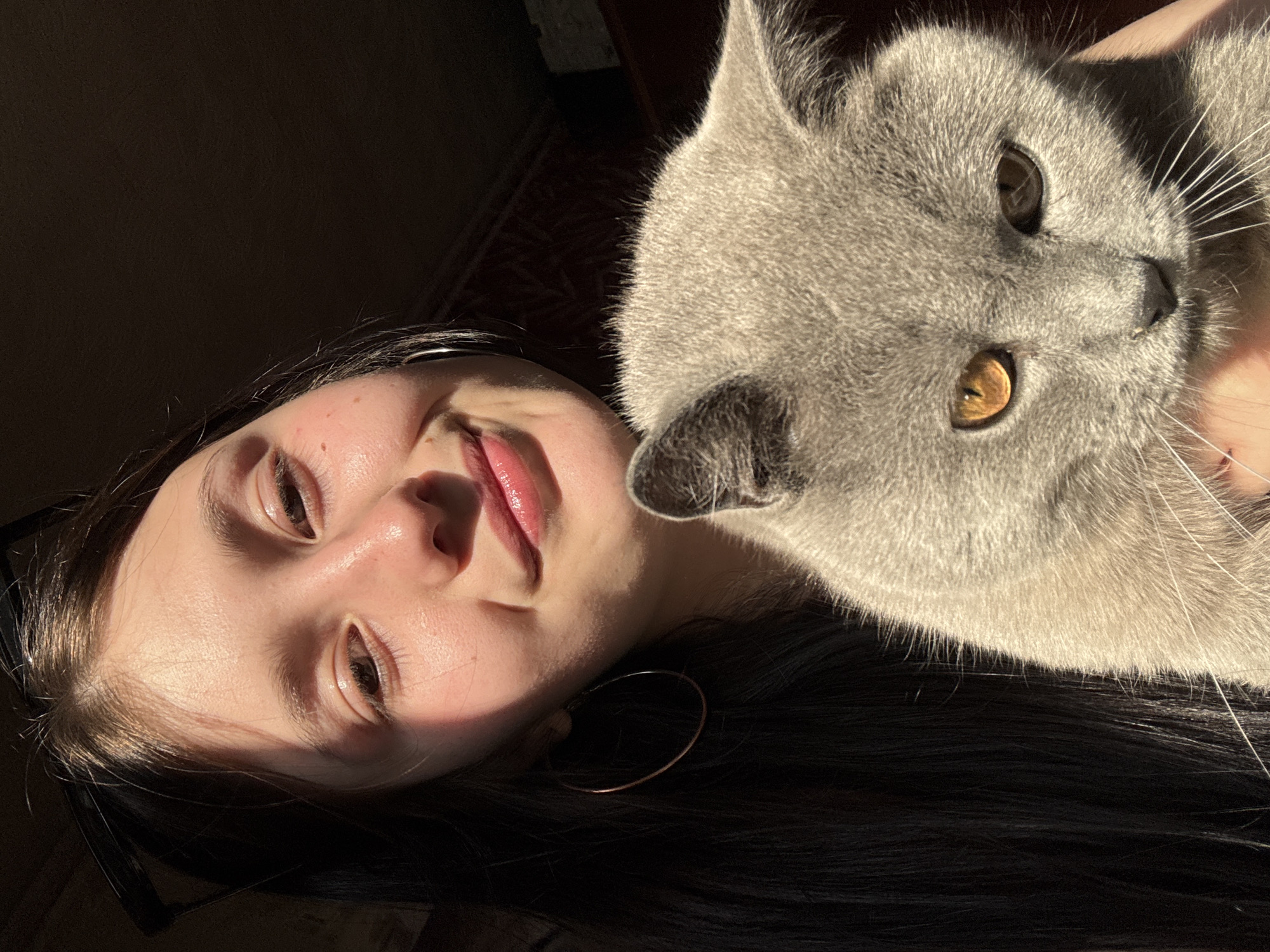 Person rests with gray cat in Foki, Russia