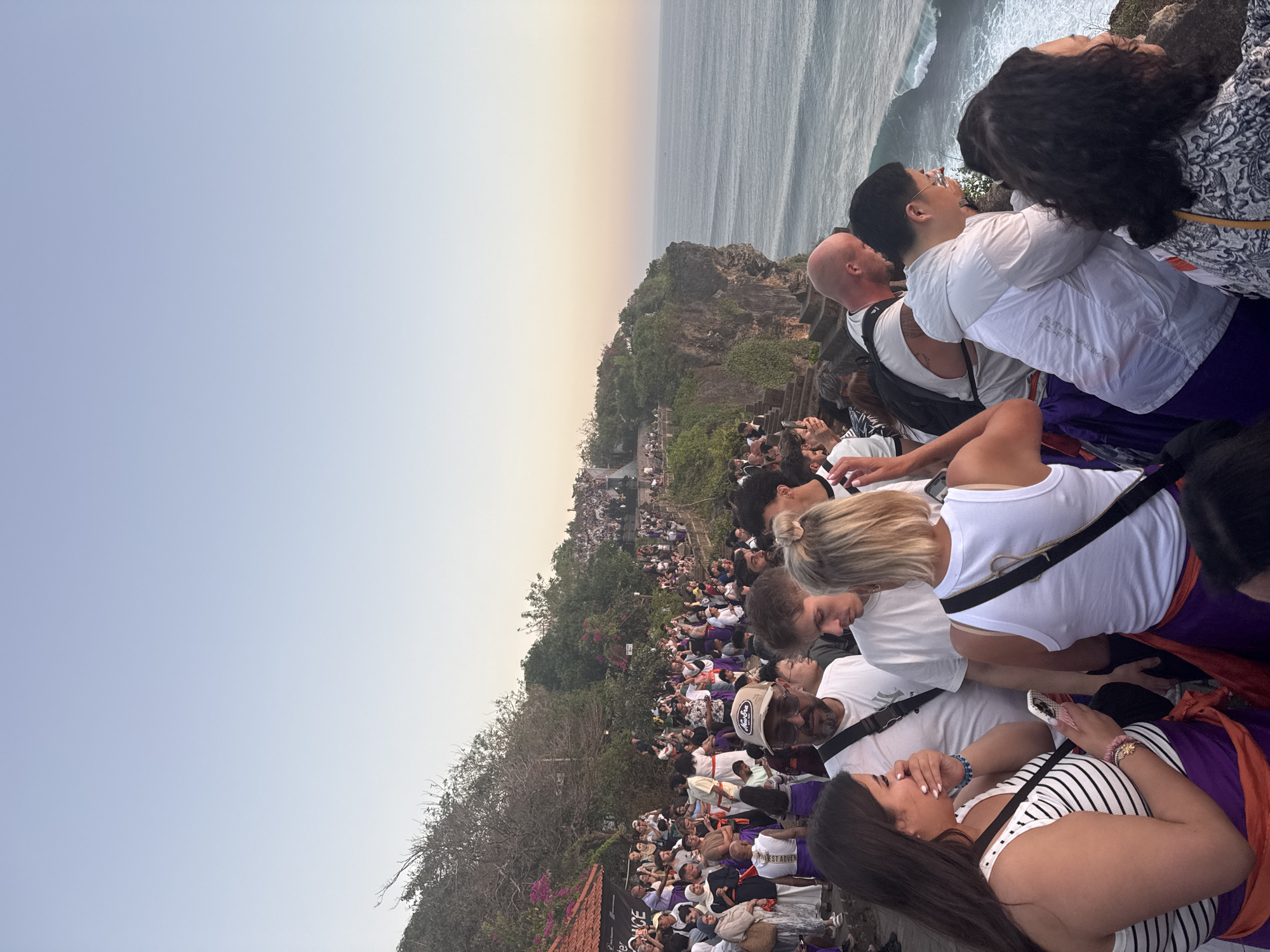 Cliffside crowd catches a vivid ocean sunset