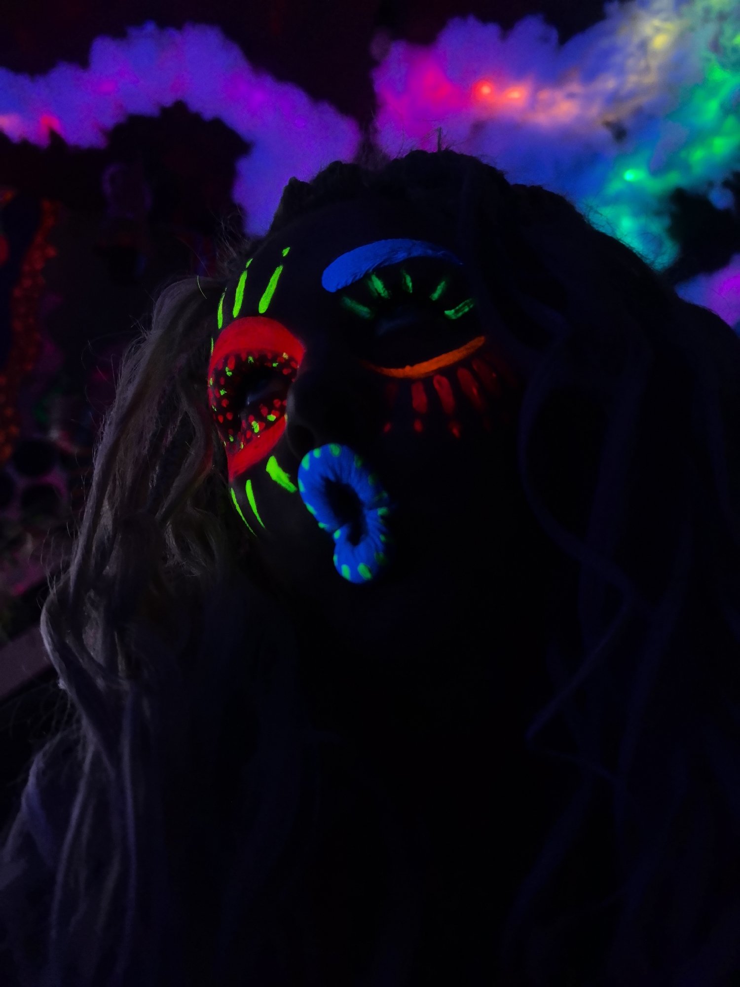 Neon face paint glows under blacklight at a night event in Russia