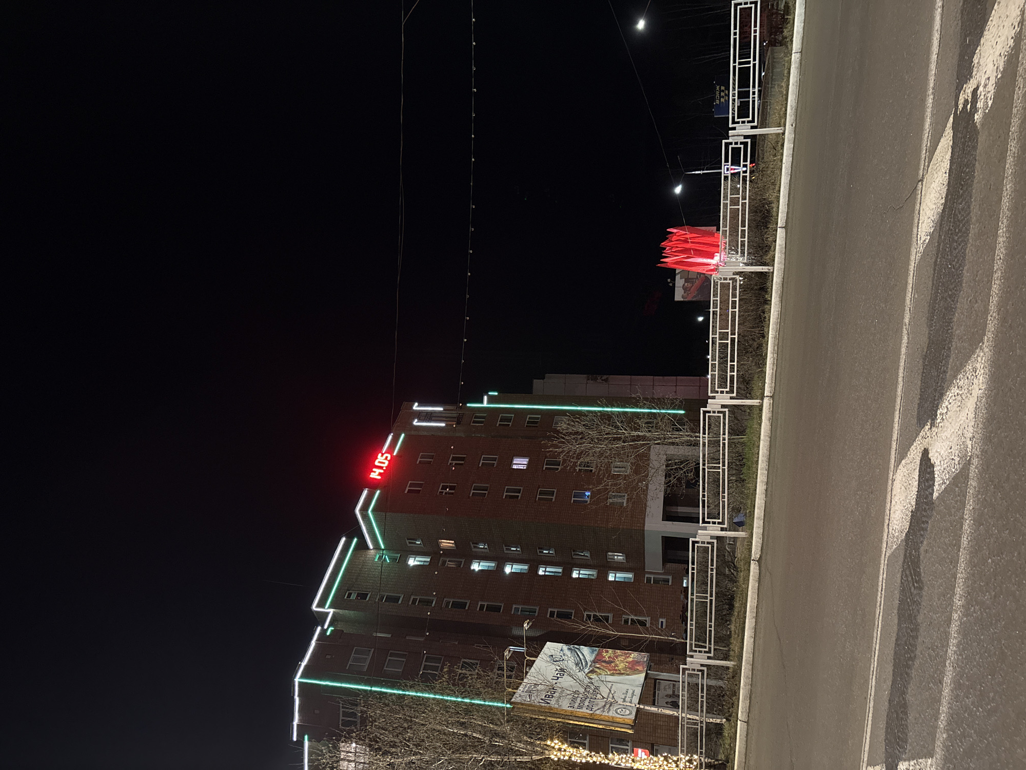 Green-lit building displays digital clock in Ust-Ilimsk nightscape