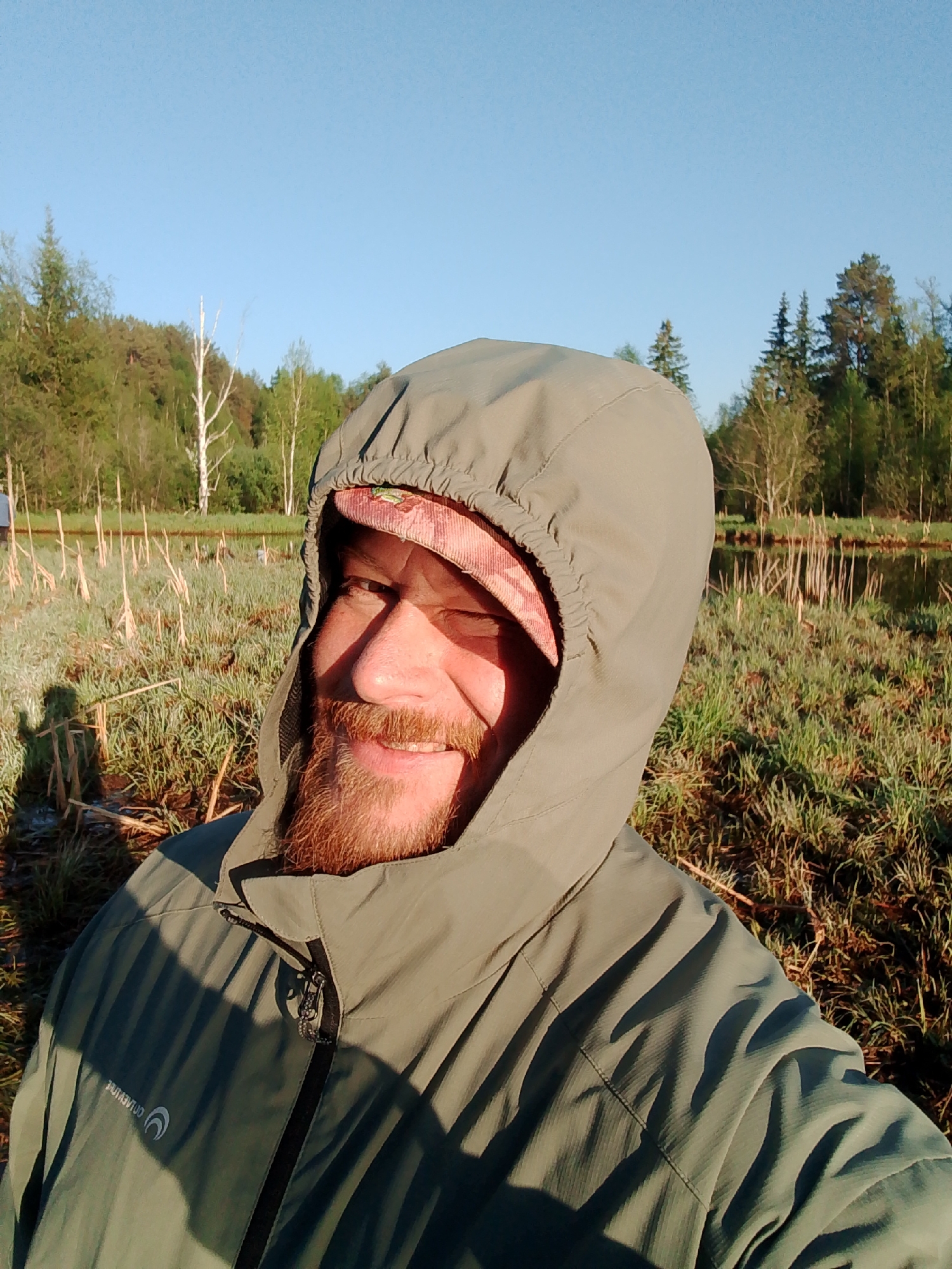 Man takes selfie in grassy field near water in Chaikovsky
