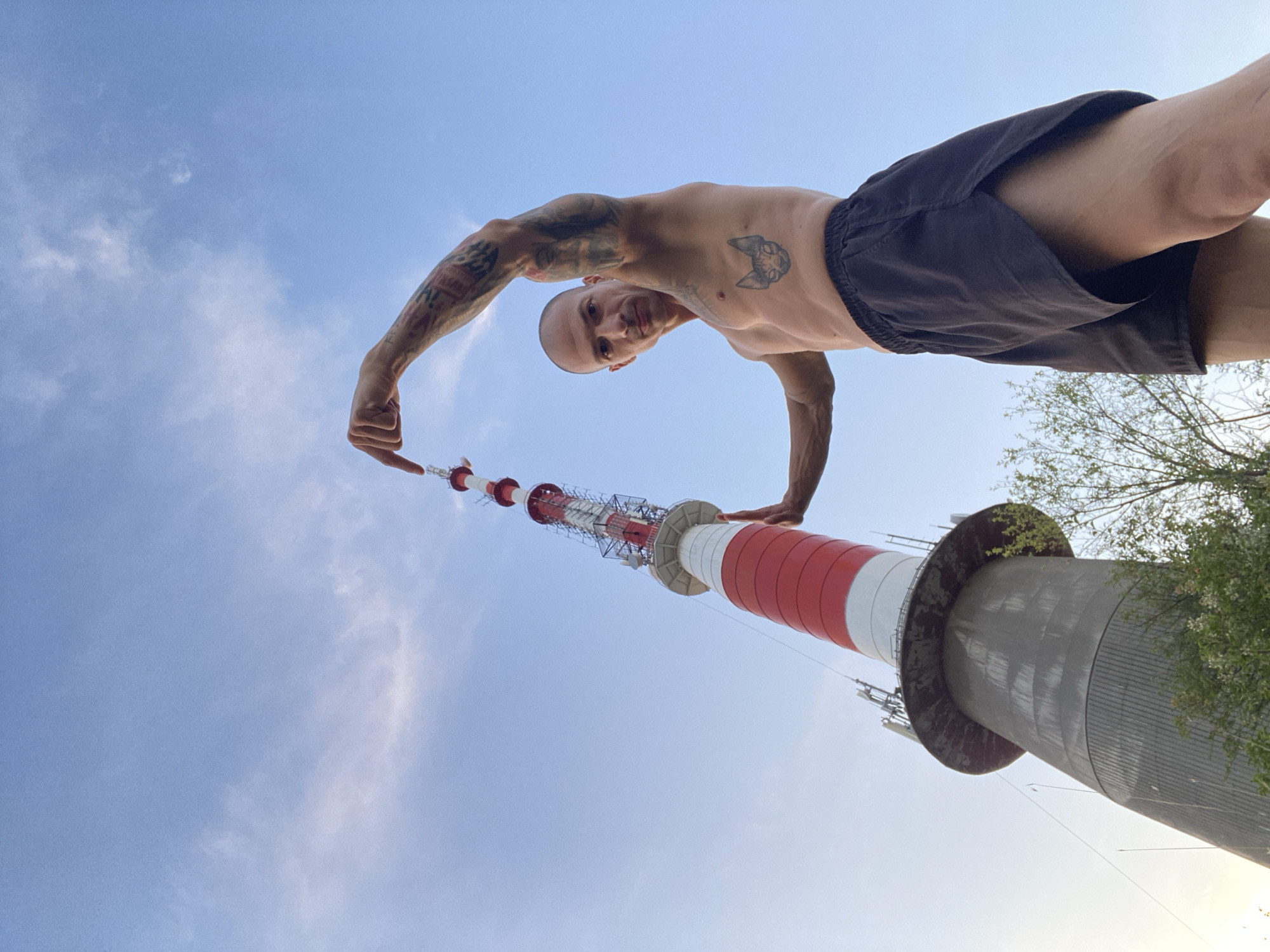 Tattooed figure poses near Pleven towers on a summer afternoon
