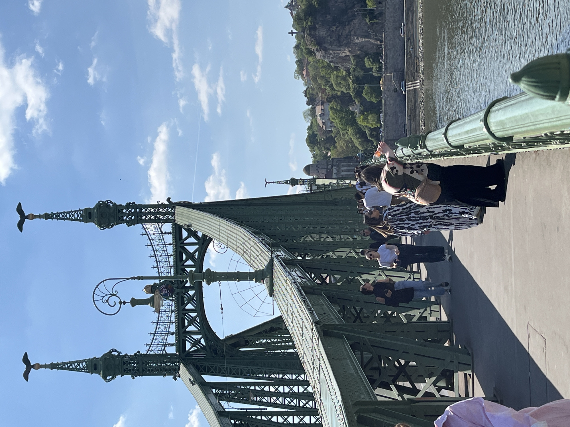 Tourists visit Liberty Bridge as cruise boat navigates Danube