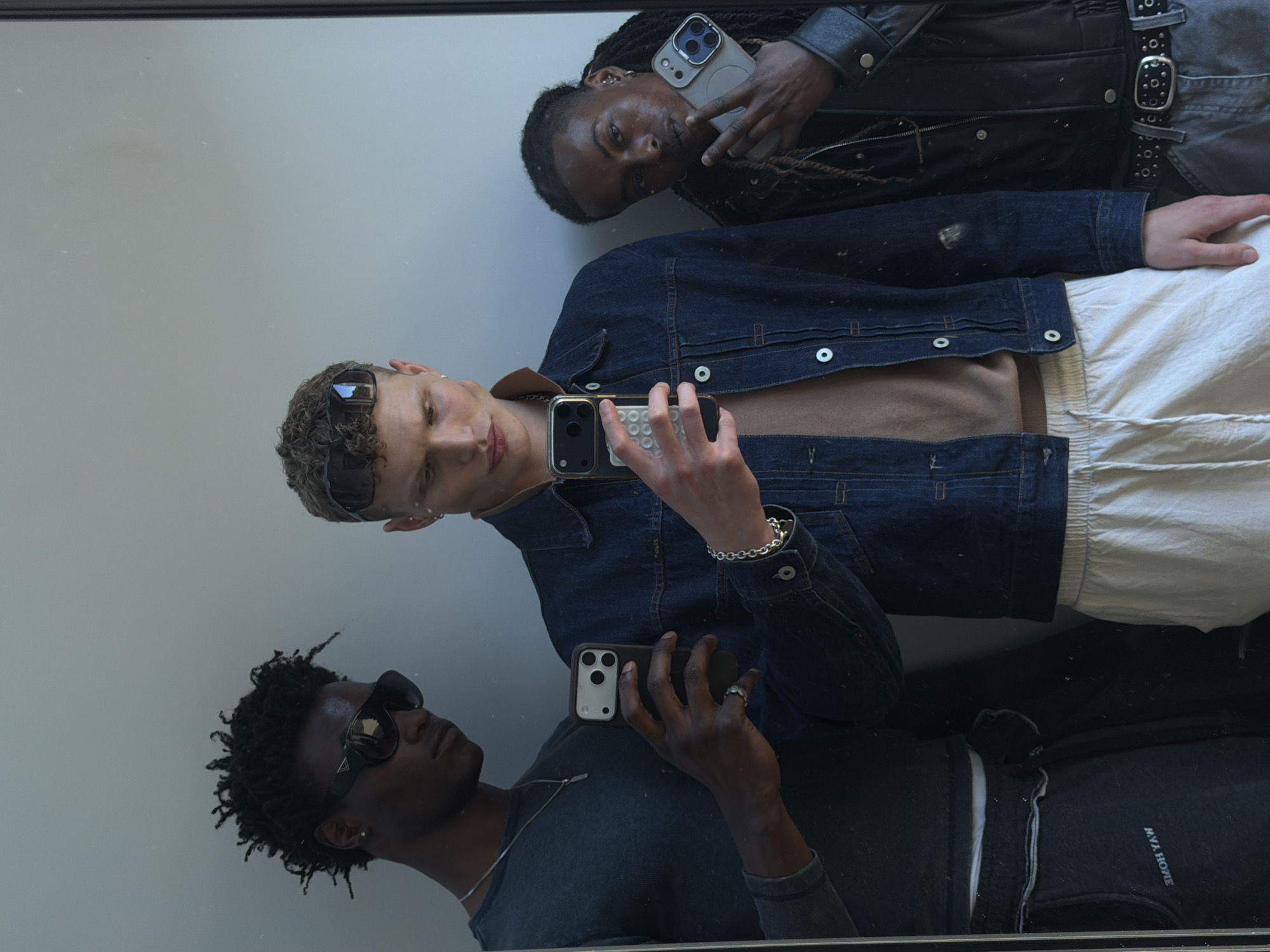 Three men take mirror selfies in London indoor location