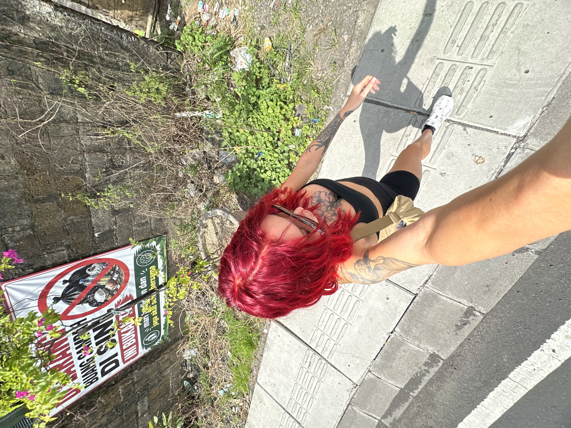 Tourist takes early morning selfies on North Kuta sidewalk