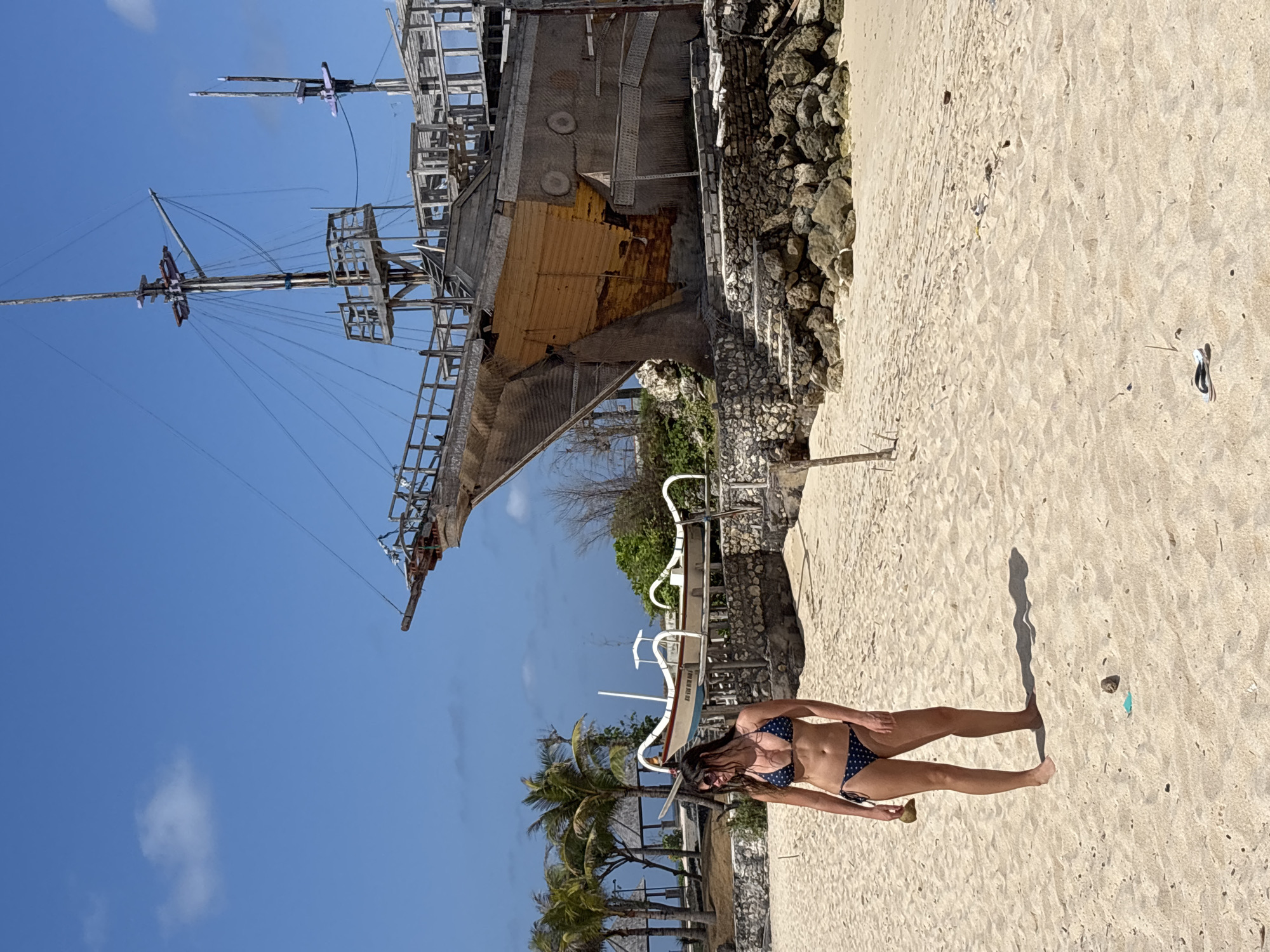 Padang Padang Beach scene: ship installation, sunbathers, Balinese landmarks