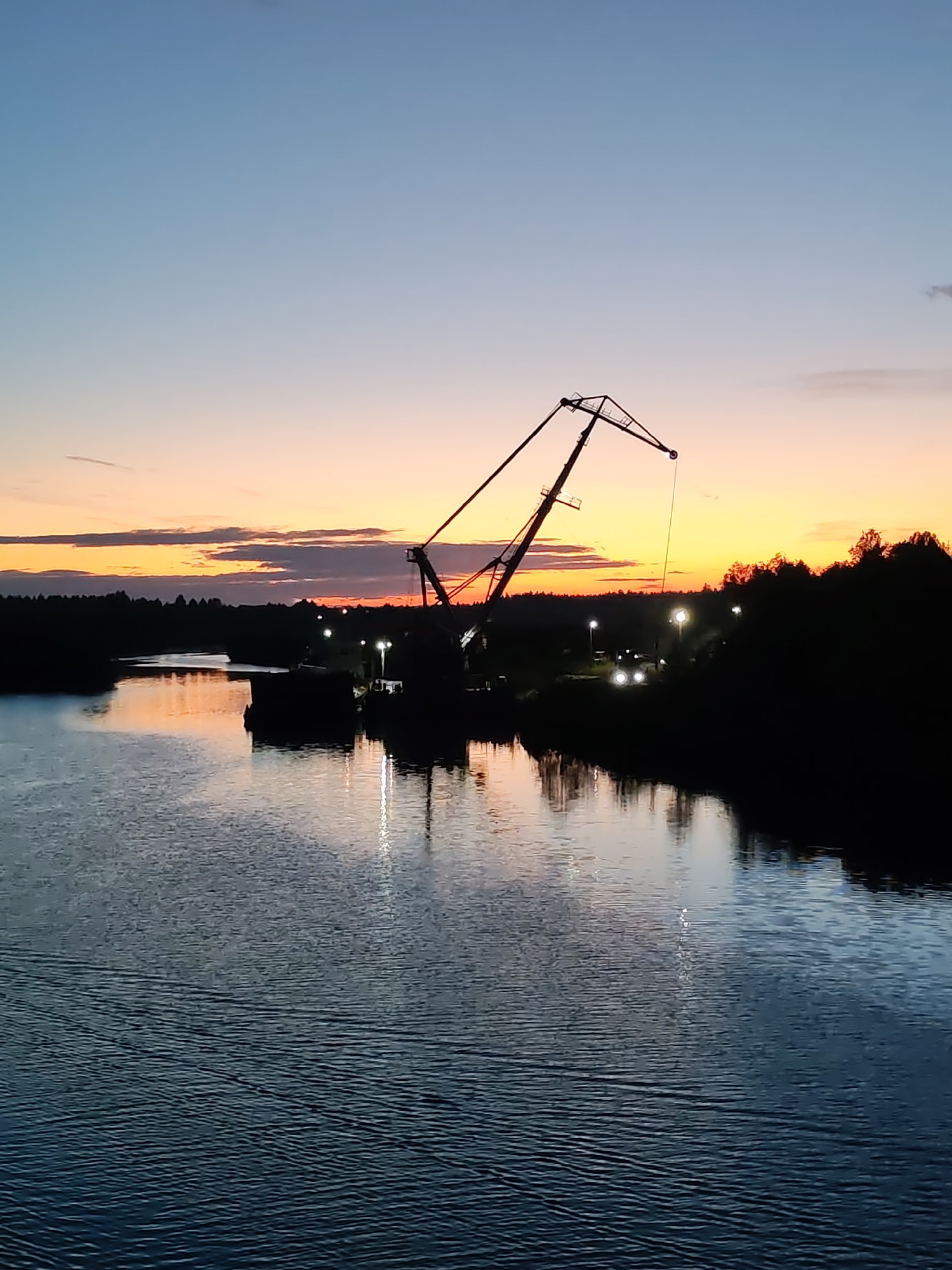 Crane barge silhouetted against sunset in Annensky Most Russia