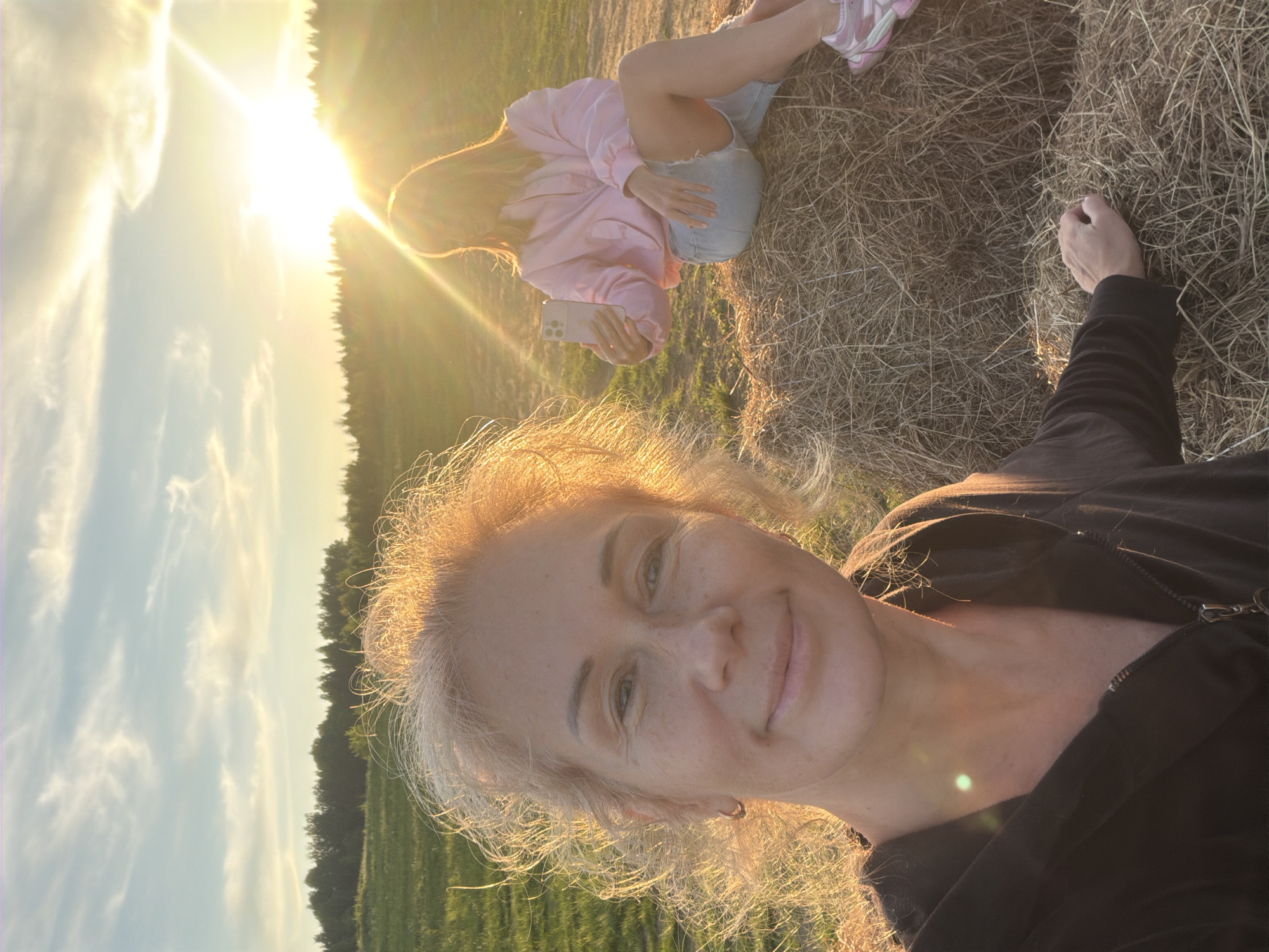 Person walks through Russian field toward hay bales at sunset