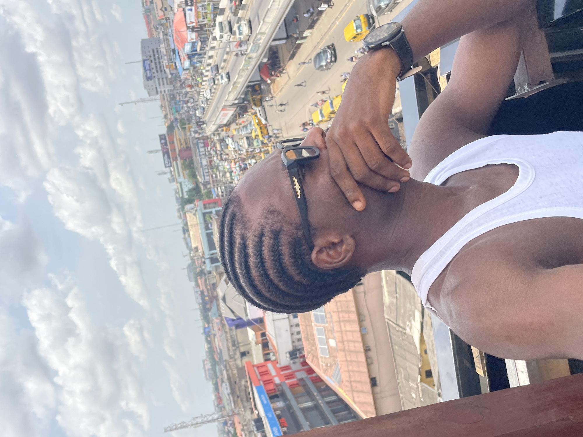Man takes selfies from rooftop overlooking busy Ikeja cityscape