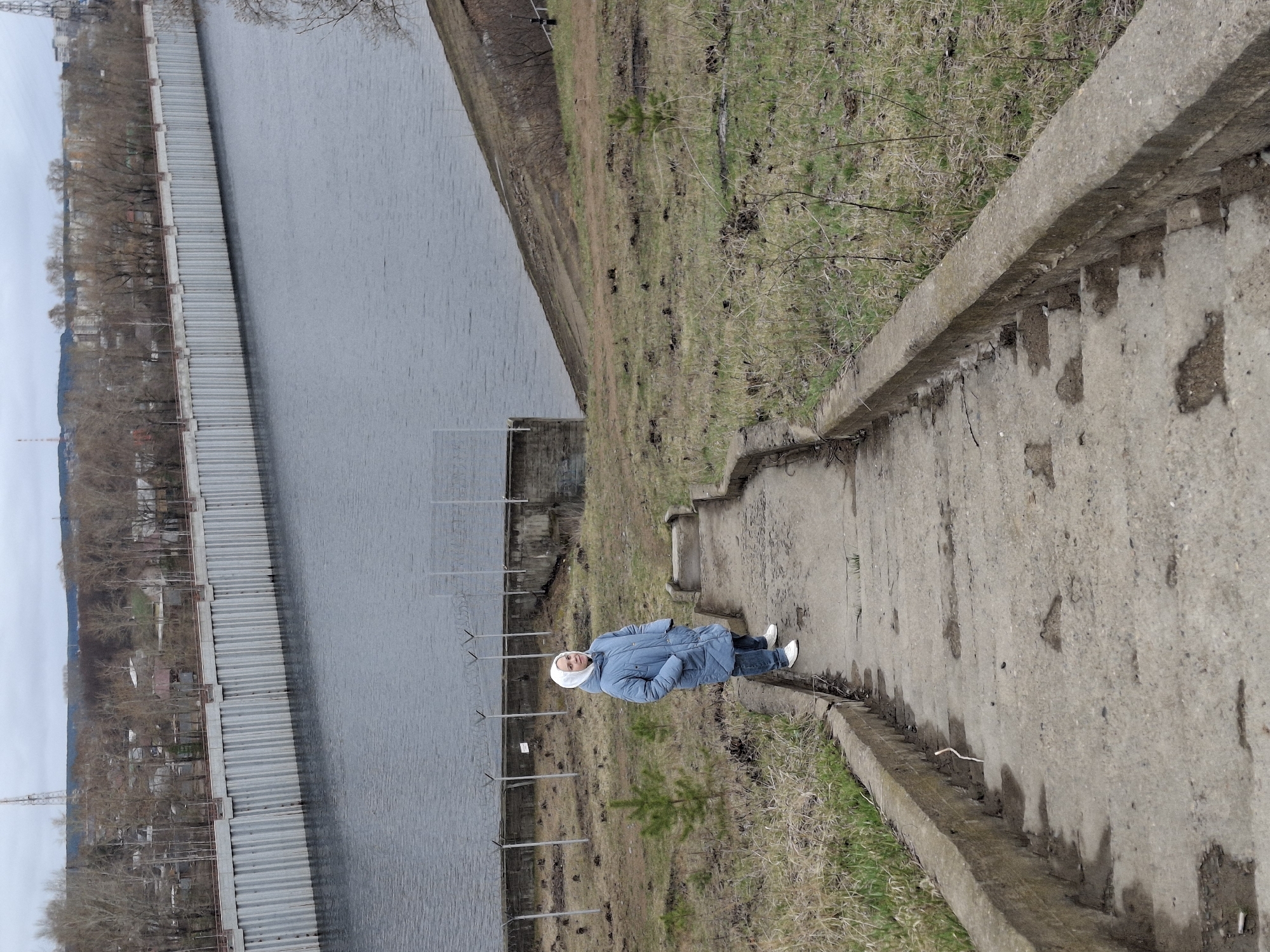 Woman walks waterside pathway in Chaikovsky, Russia