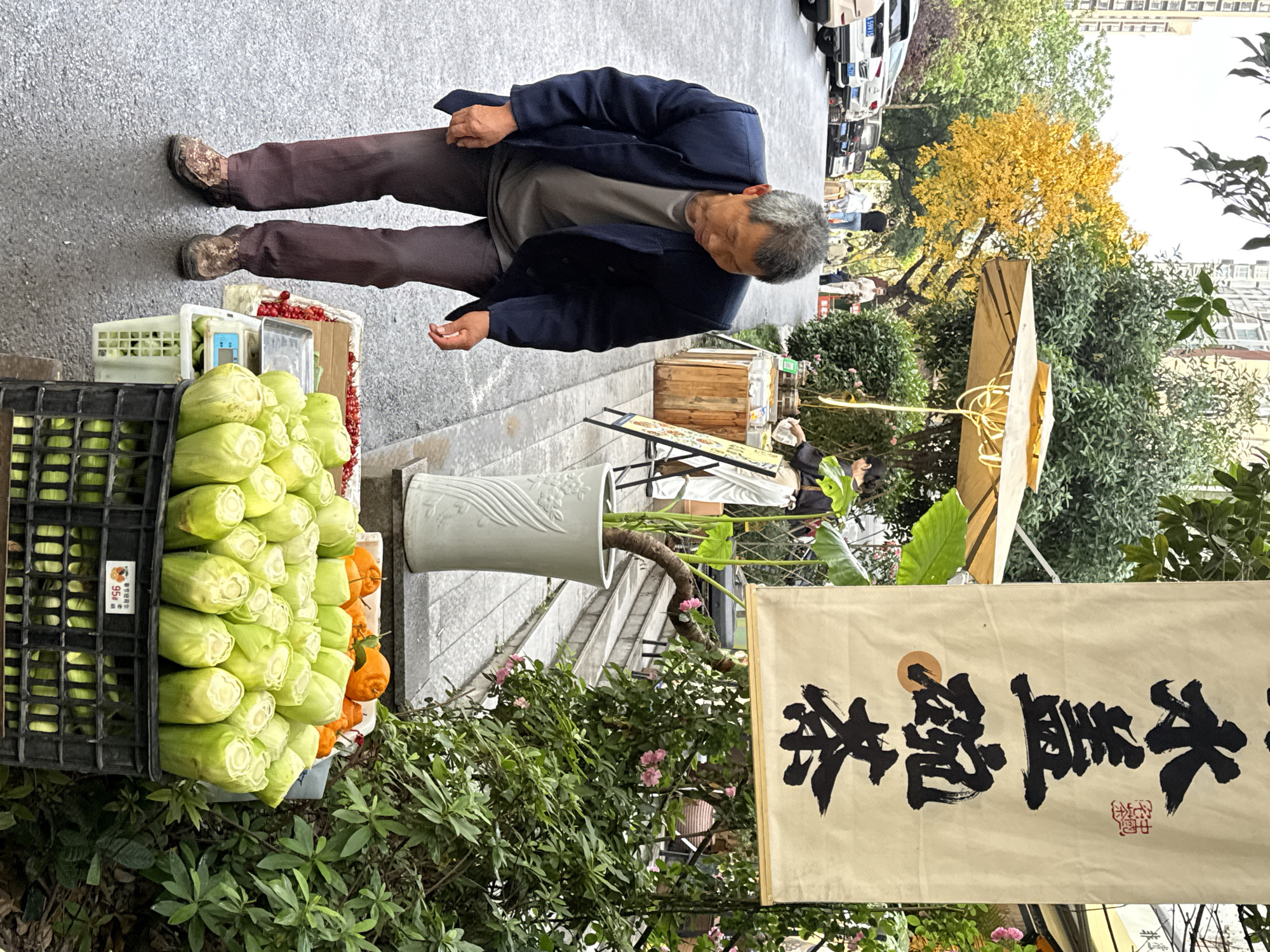 Elderly man stands by street produce display in Yuzhong District