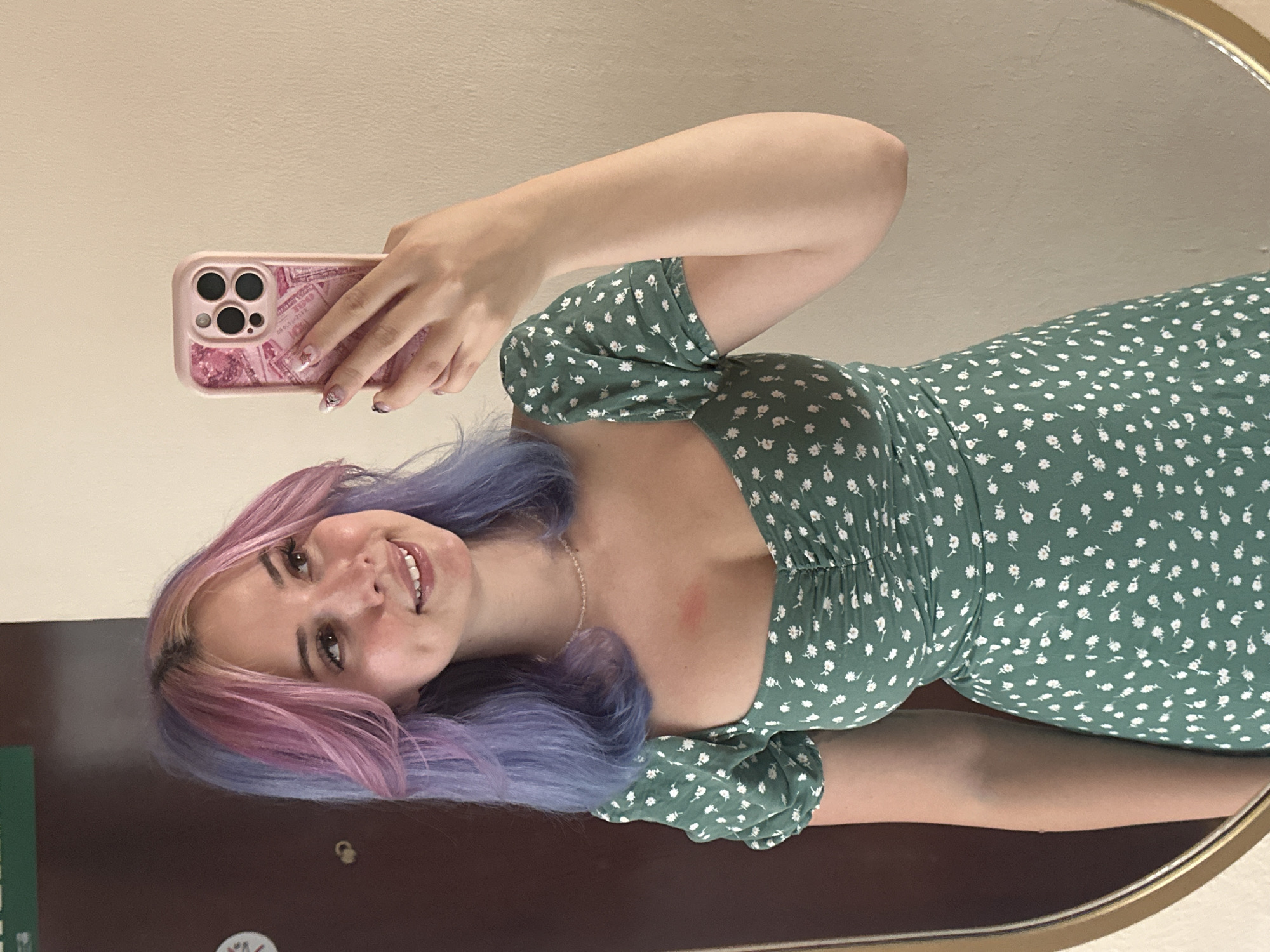 Woman takes mirror selfie in colorful hair, floral dress