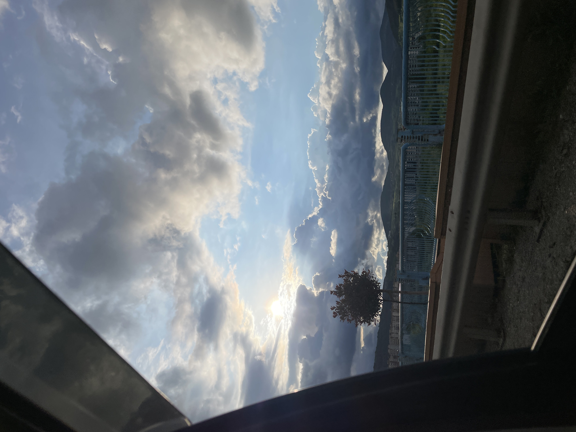 Driver documents cloudy afternoon sky, parked BMW in Kardzhali