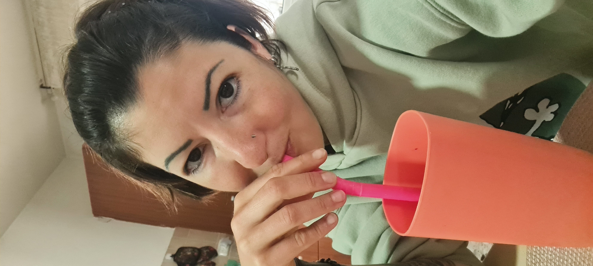 Woman drinks from orange cup in Nahariyya