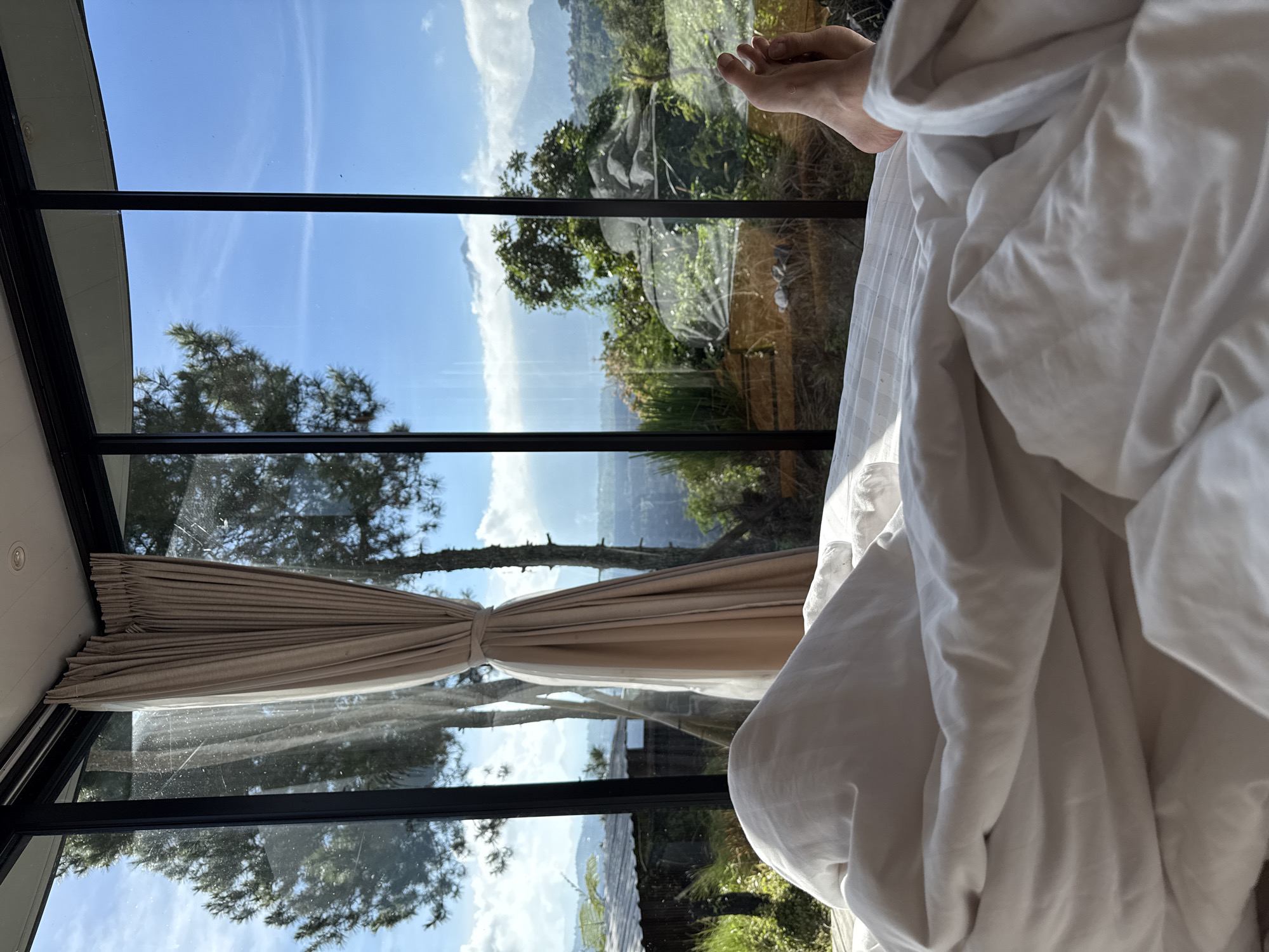 Person in bed gazing through bedroom window in Kintamani