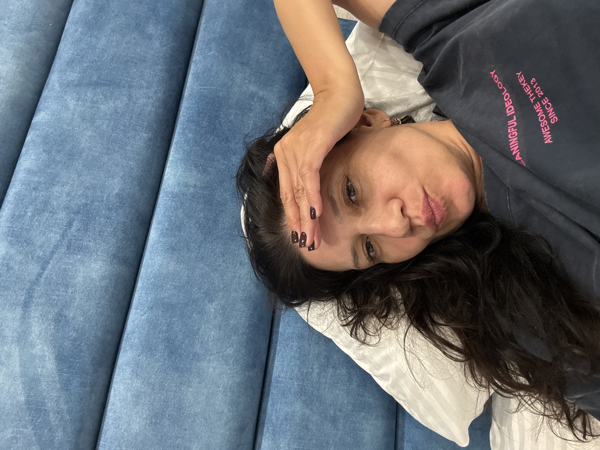 Resting in bed, hand on forehead, blue headboard behind