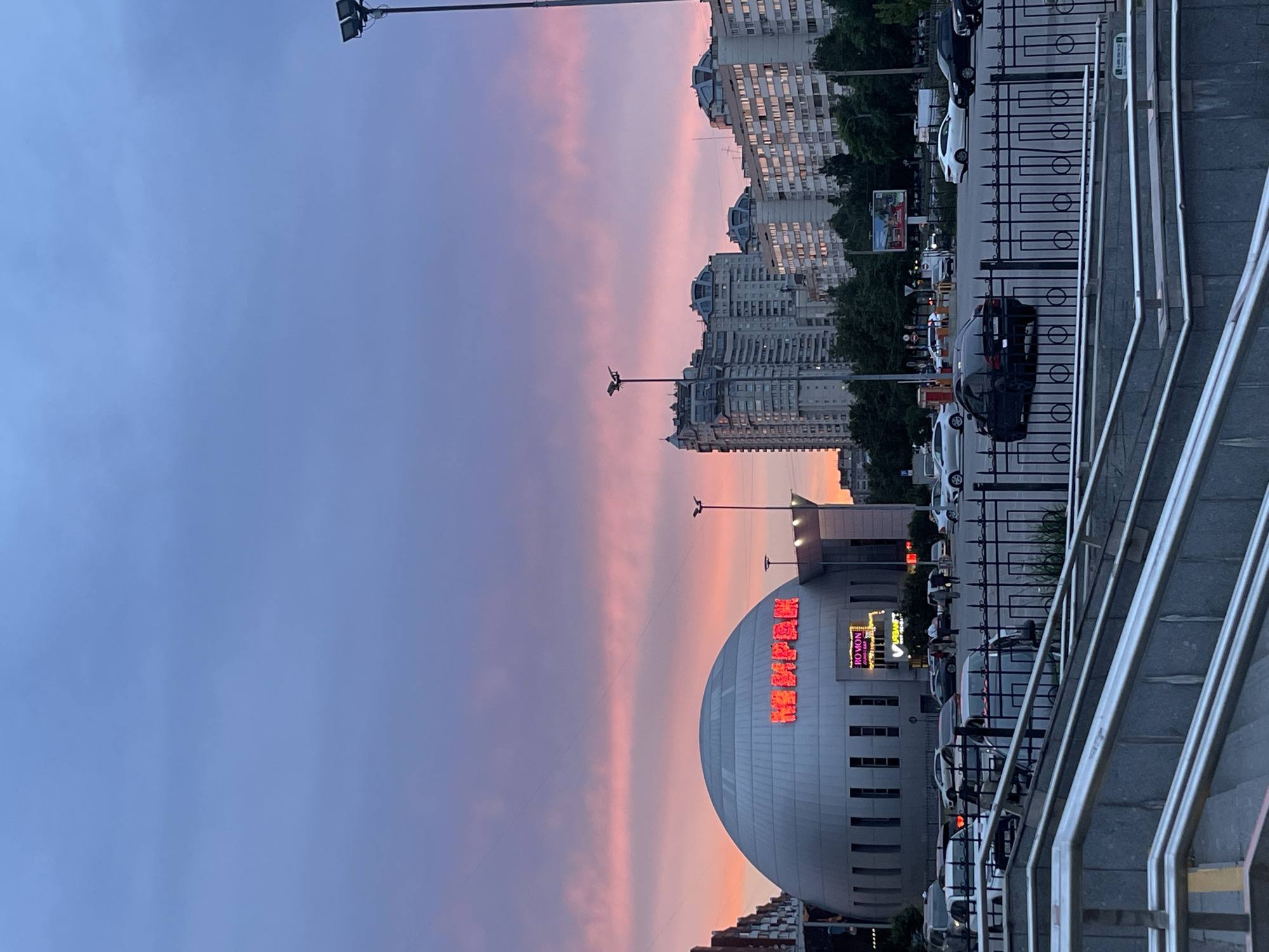 Dusk in a Soviet-era city district, neon Cyrillic signs lit up