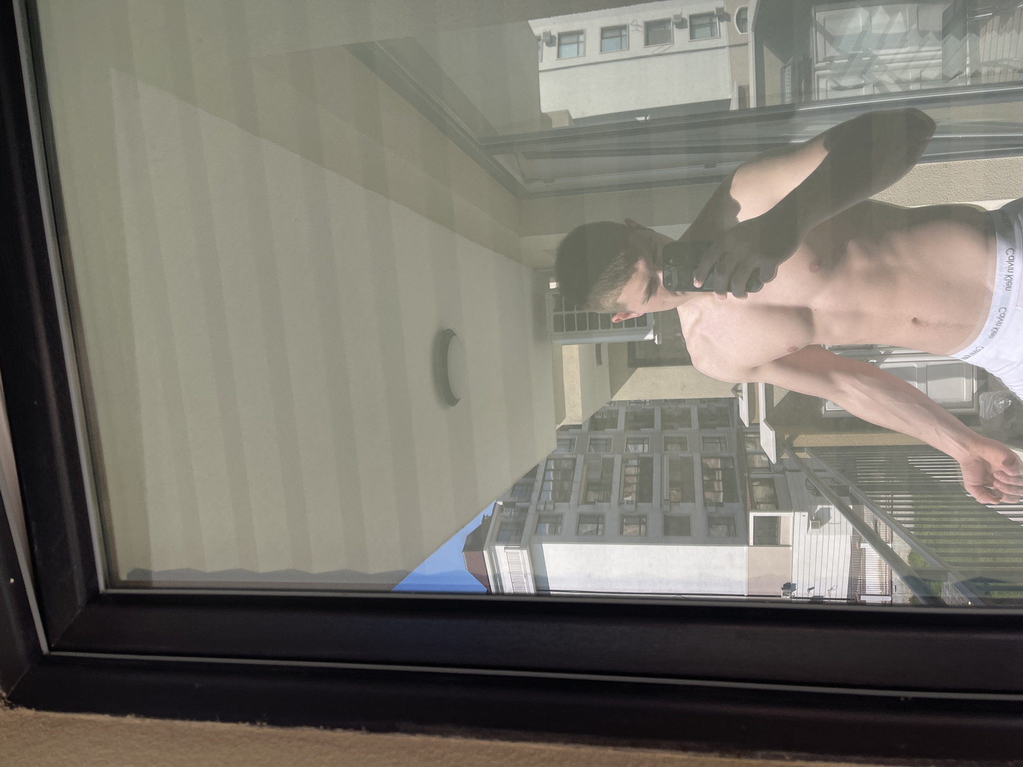 Window reflection captures smartphone user in Varna residential area
