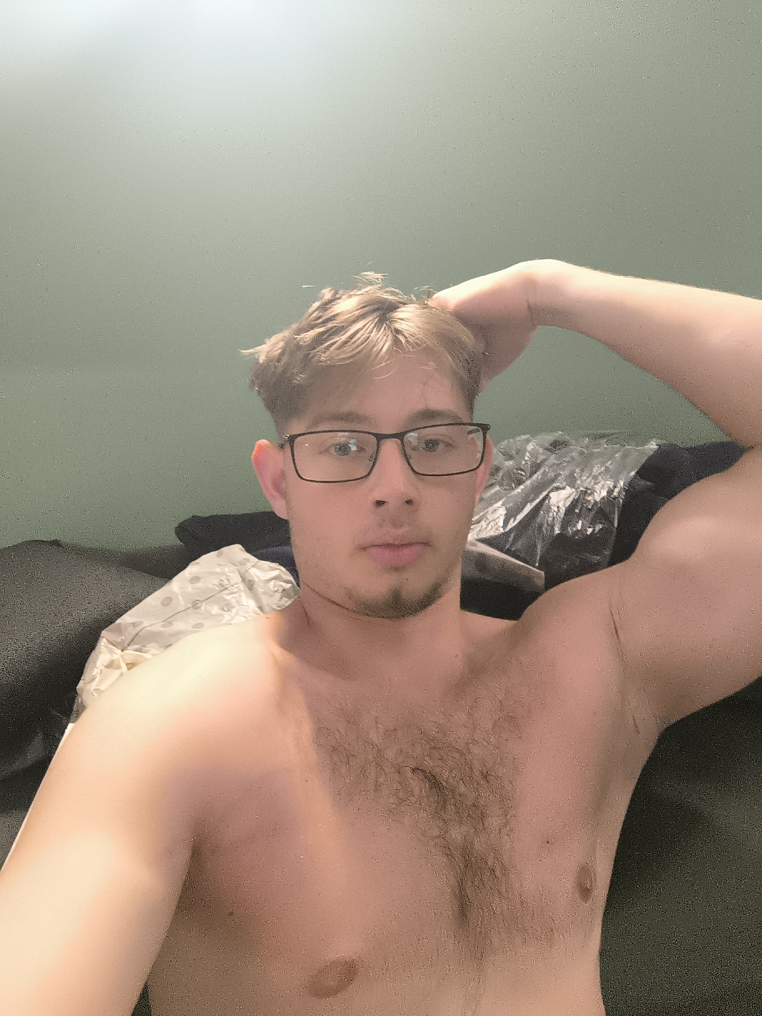 Man poses shirtless on couch in Sofia apartment