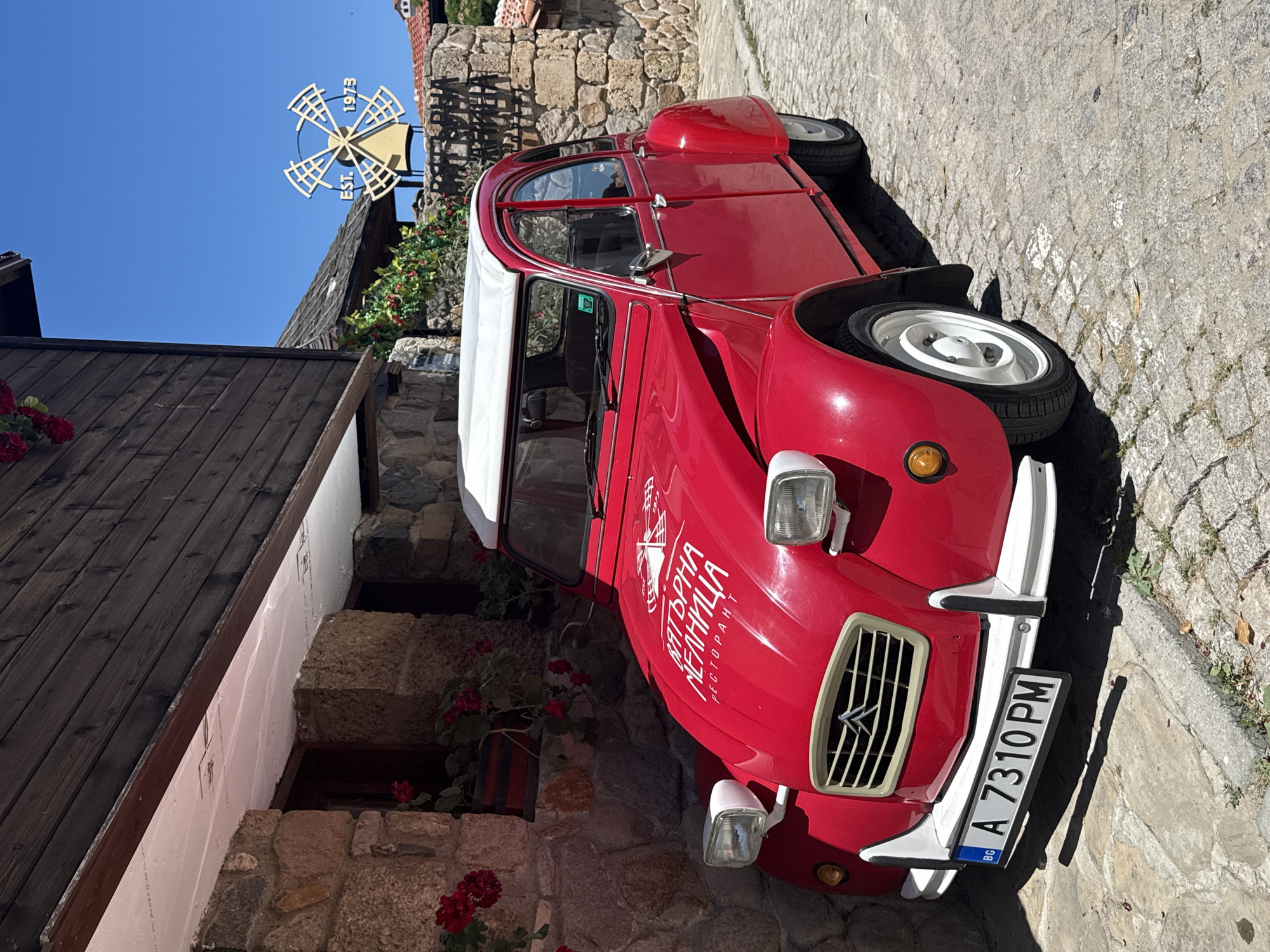 Red vintage Citroën 2CV parked on cobblestone street