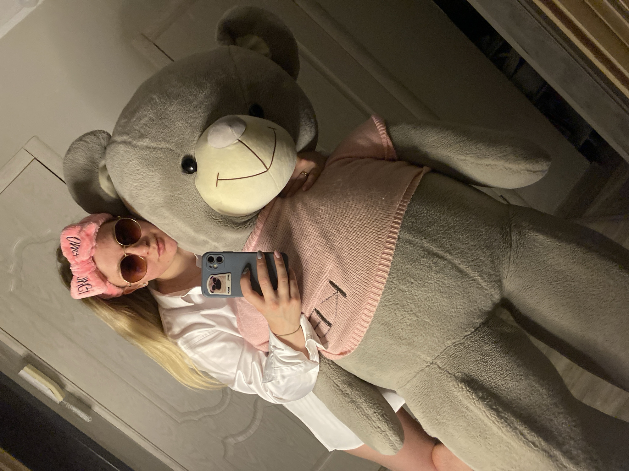 Young woman photographed with teddy bear, pink headband indoors