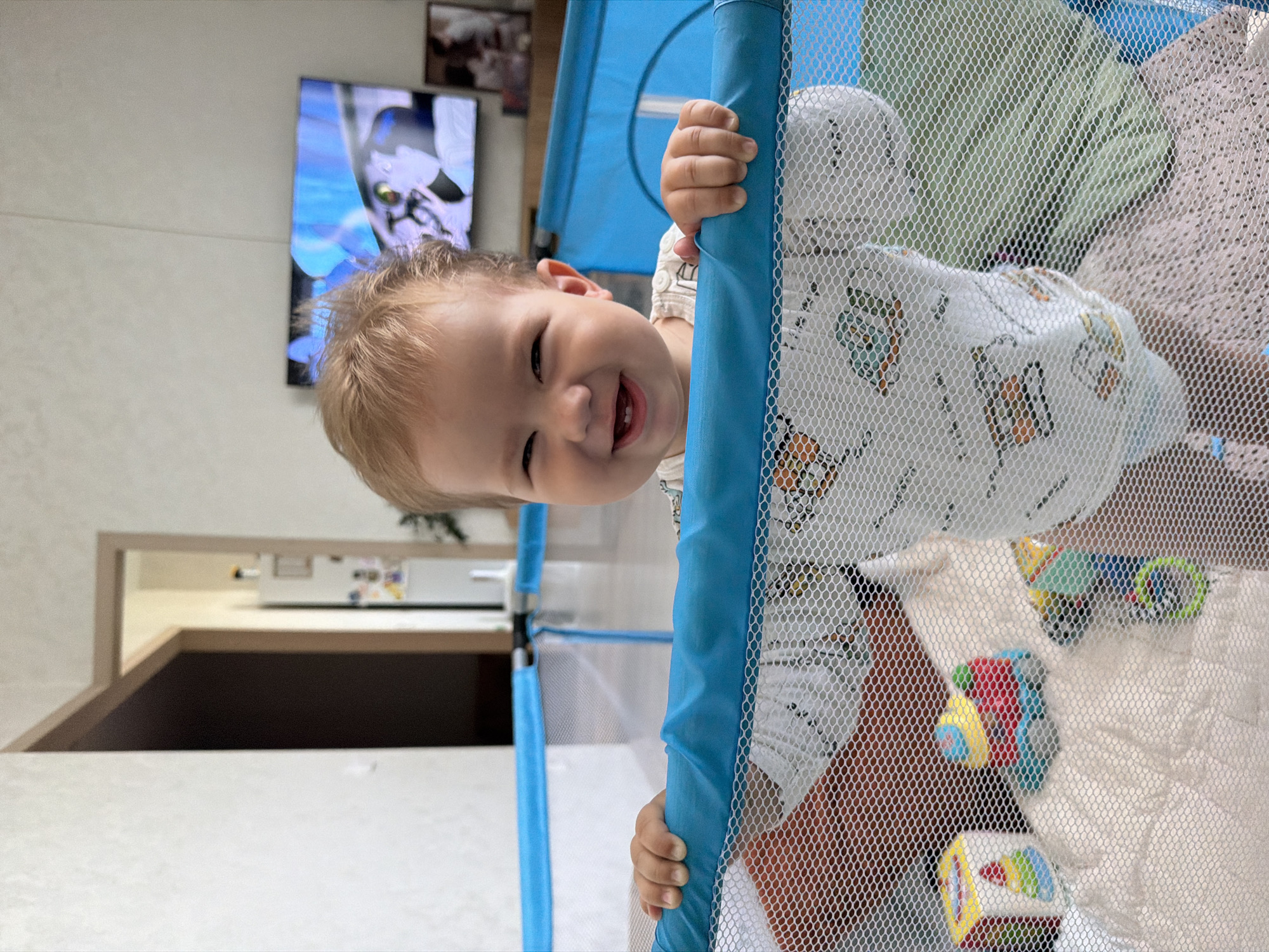 Baby plays in a Kazan living room while Lilo & Stitch runs on TV