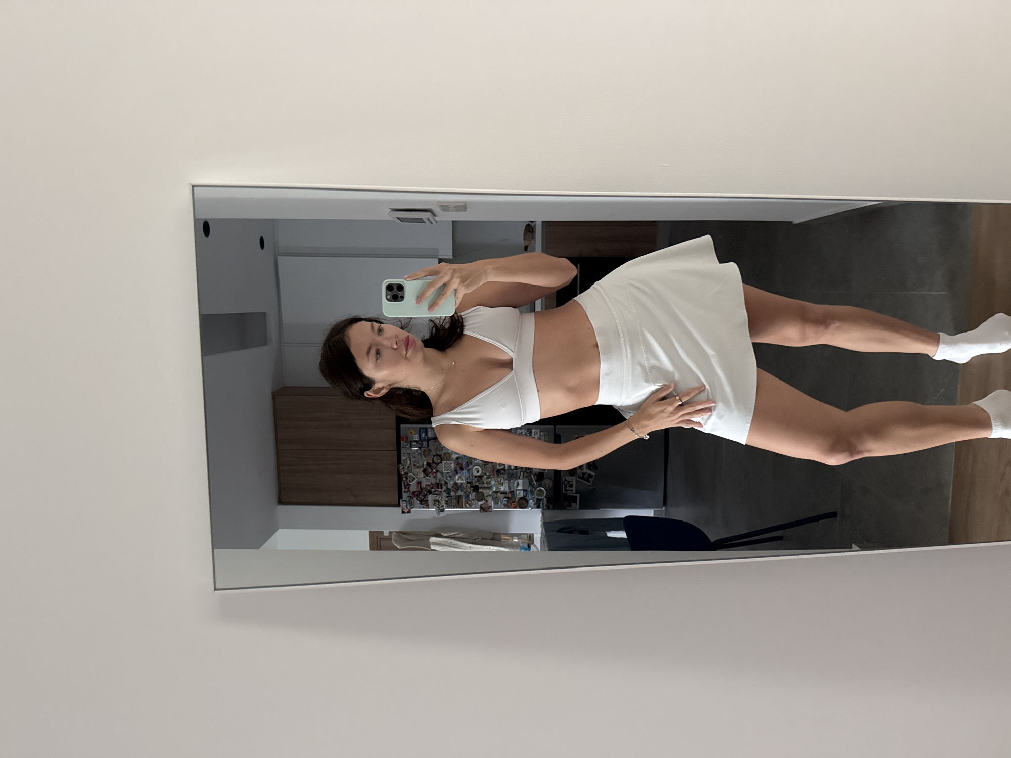 Woman takes mirror selfie in white athletic wear
