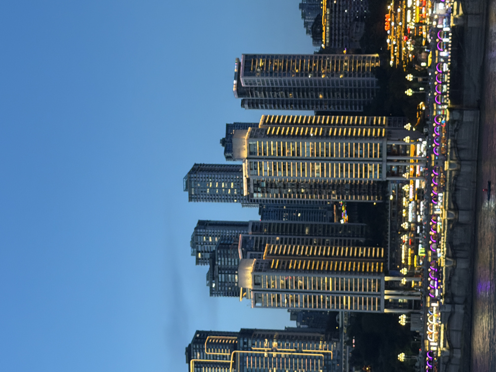 Chongqing's Raffles City towers glow red over a busy riverfront