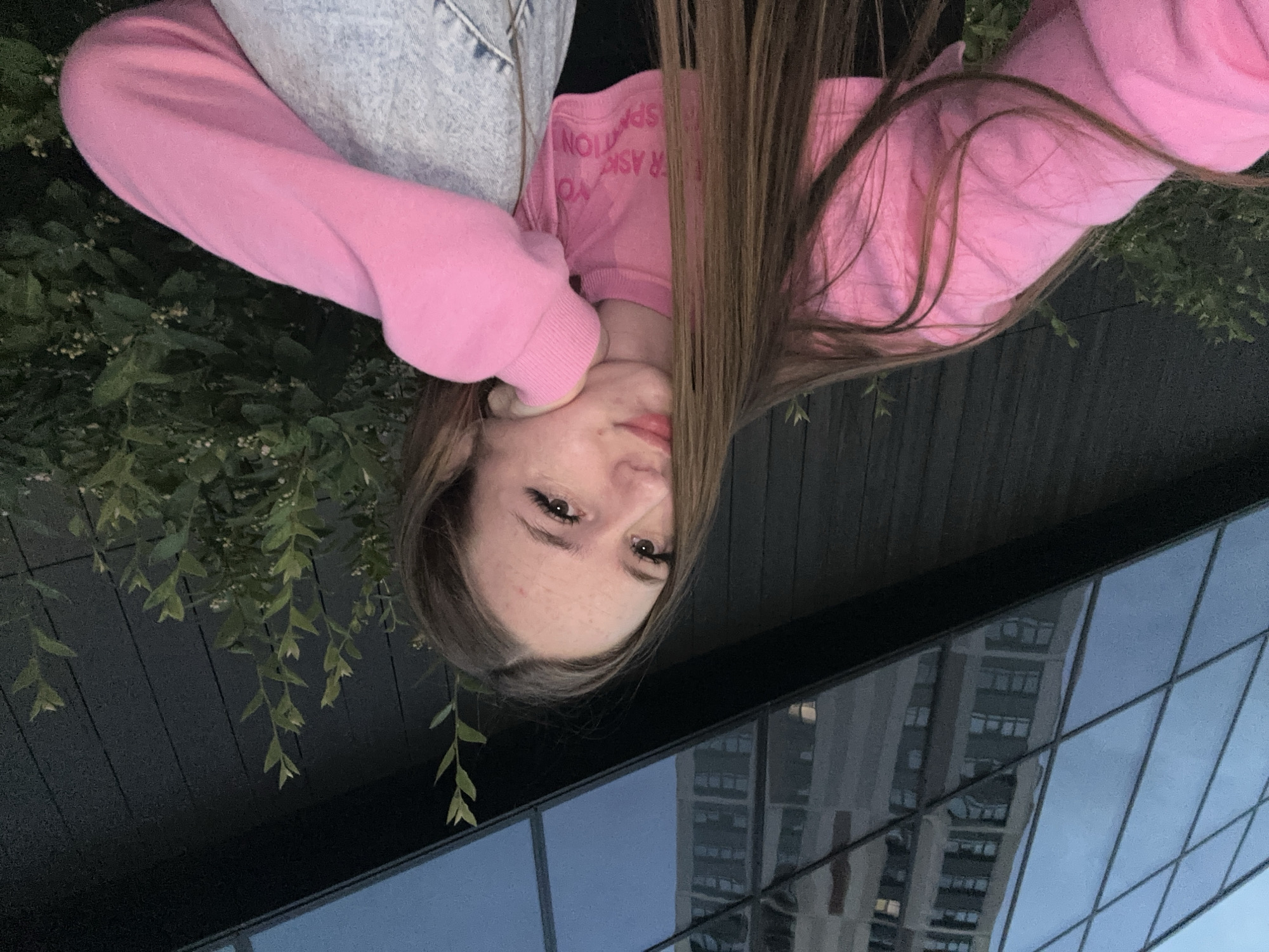 Woman in pink sweatshirt takes multiple selfies around city