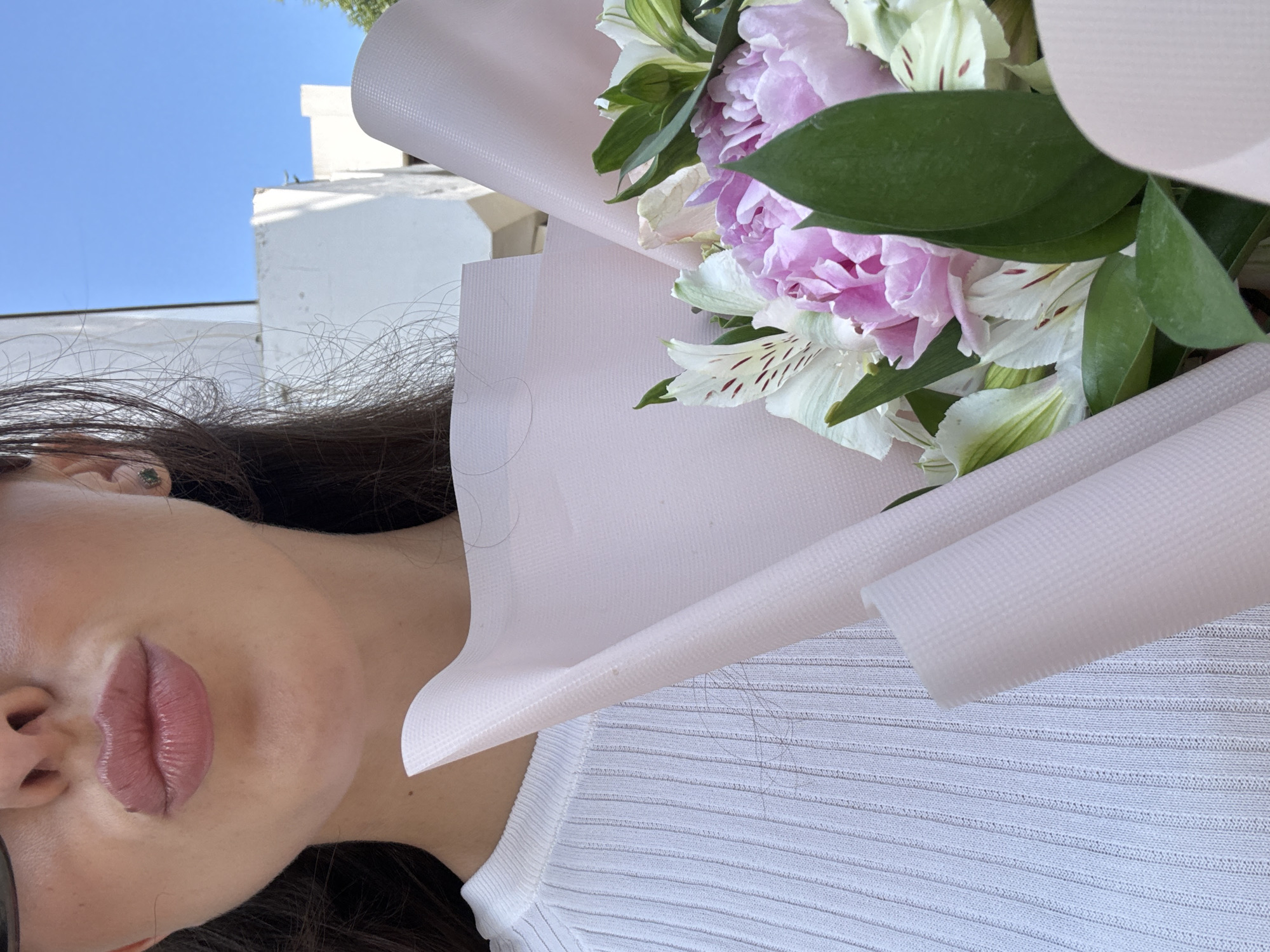 Woman carries flower bouquet through sunny Holon streets