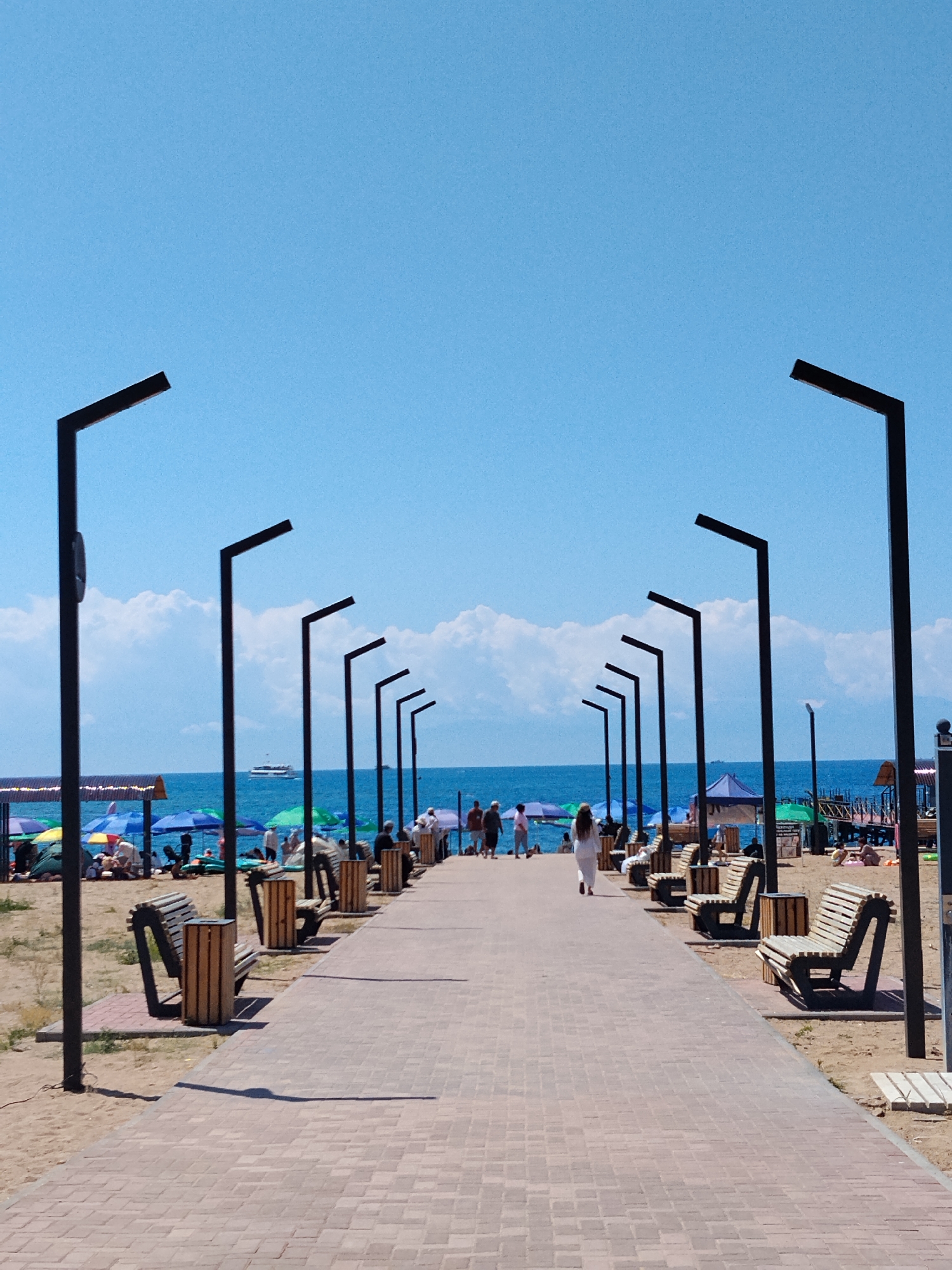 Crowded beach day with waterfront walkway and nearby food stalls