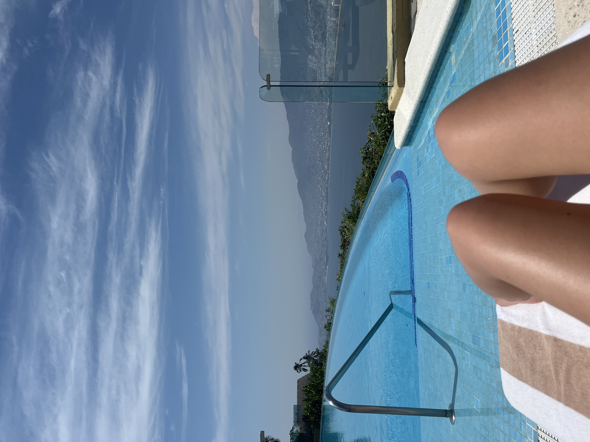 Person relaxes at infinity pool overlooking Acapulco coastline