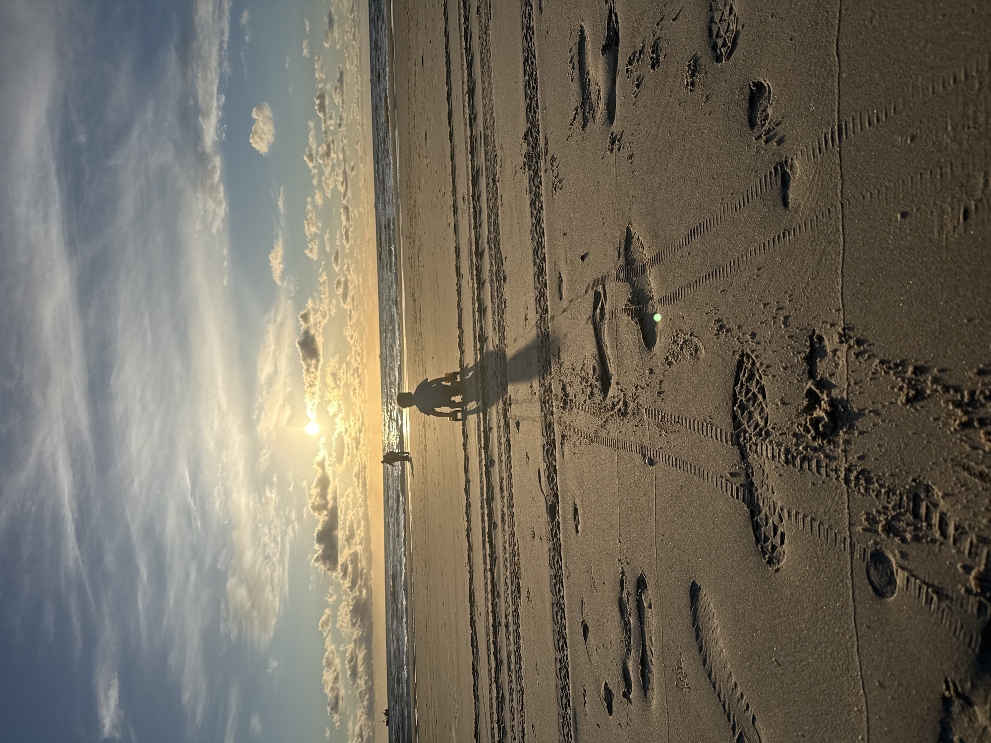 Child plays with toy truck on Petten beach at sunset