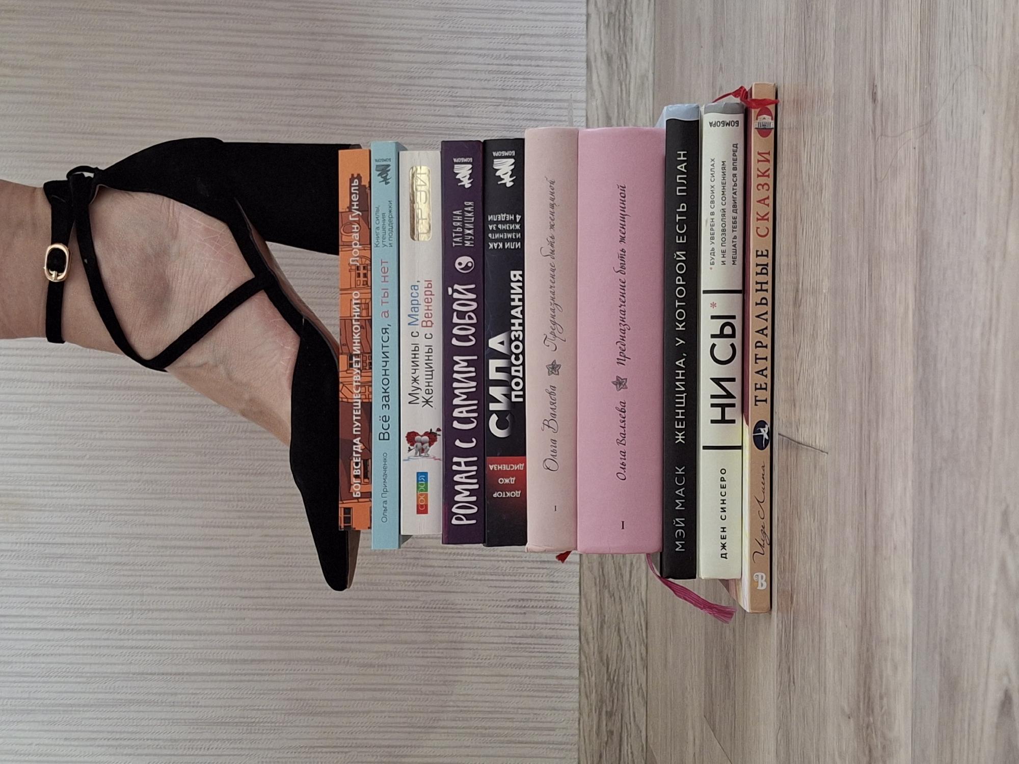 Woman in heels poses with books on wooden floor