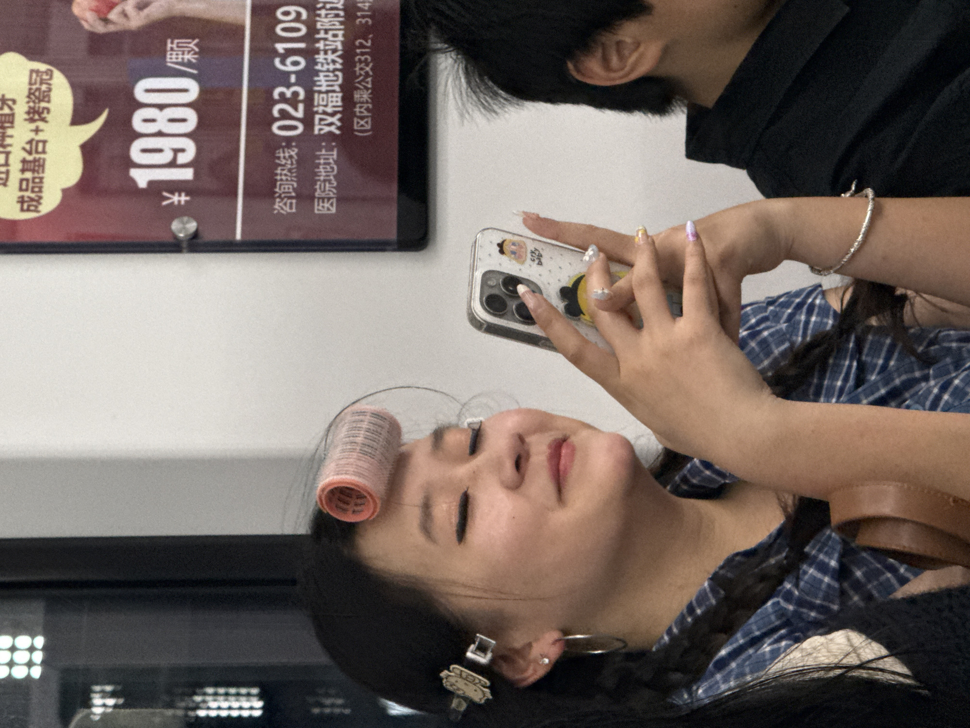 Commuter with hair roller uses phone on Shuangfu train