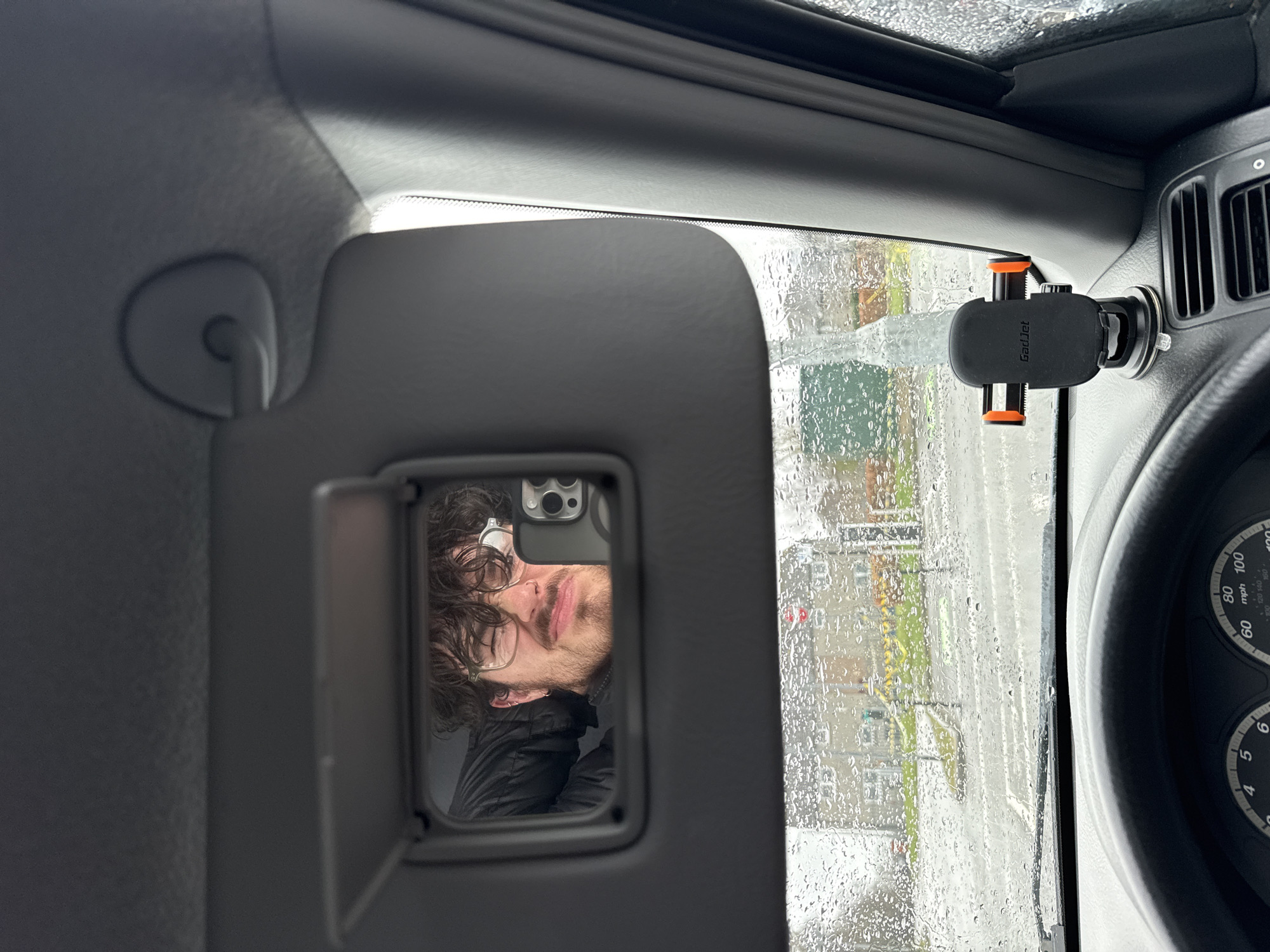 Man reflected in car mirror during rainy day
