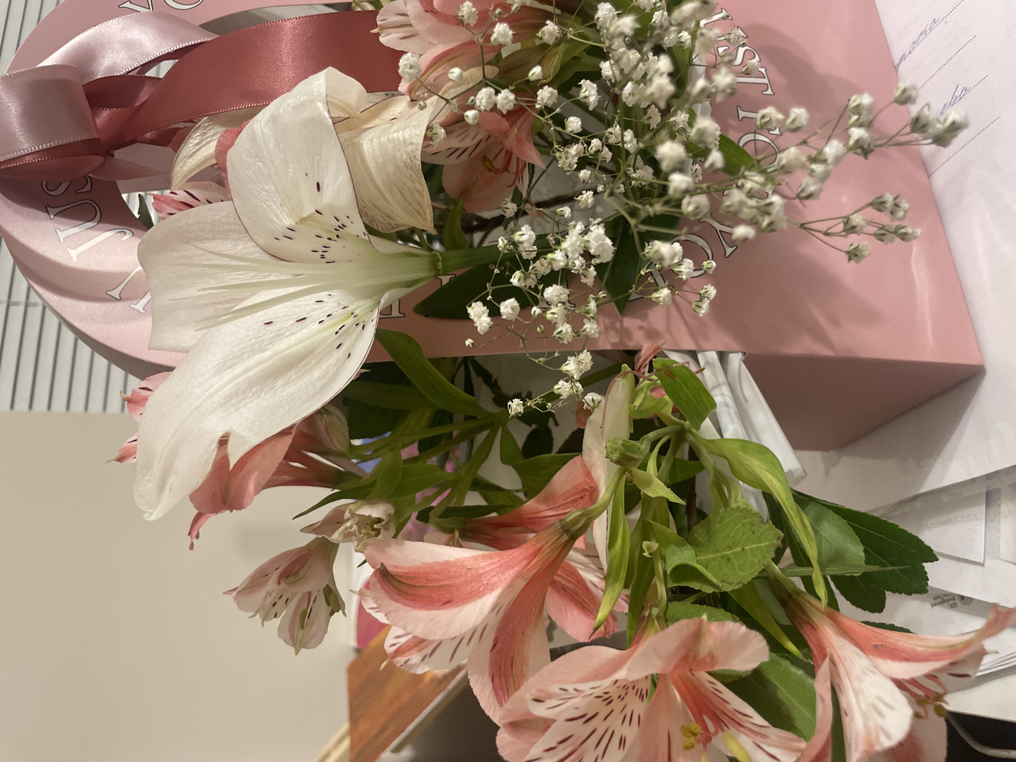 Flowers, a gift bag, and a relaxed tabby cat at home