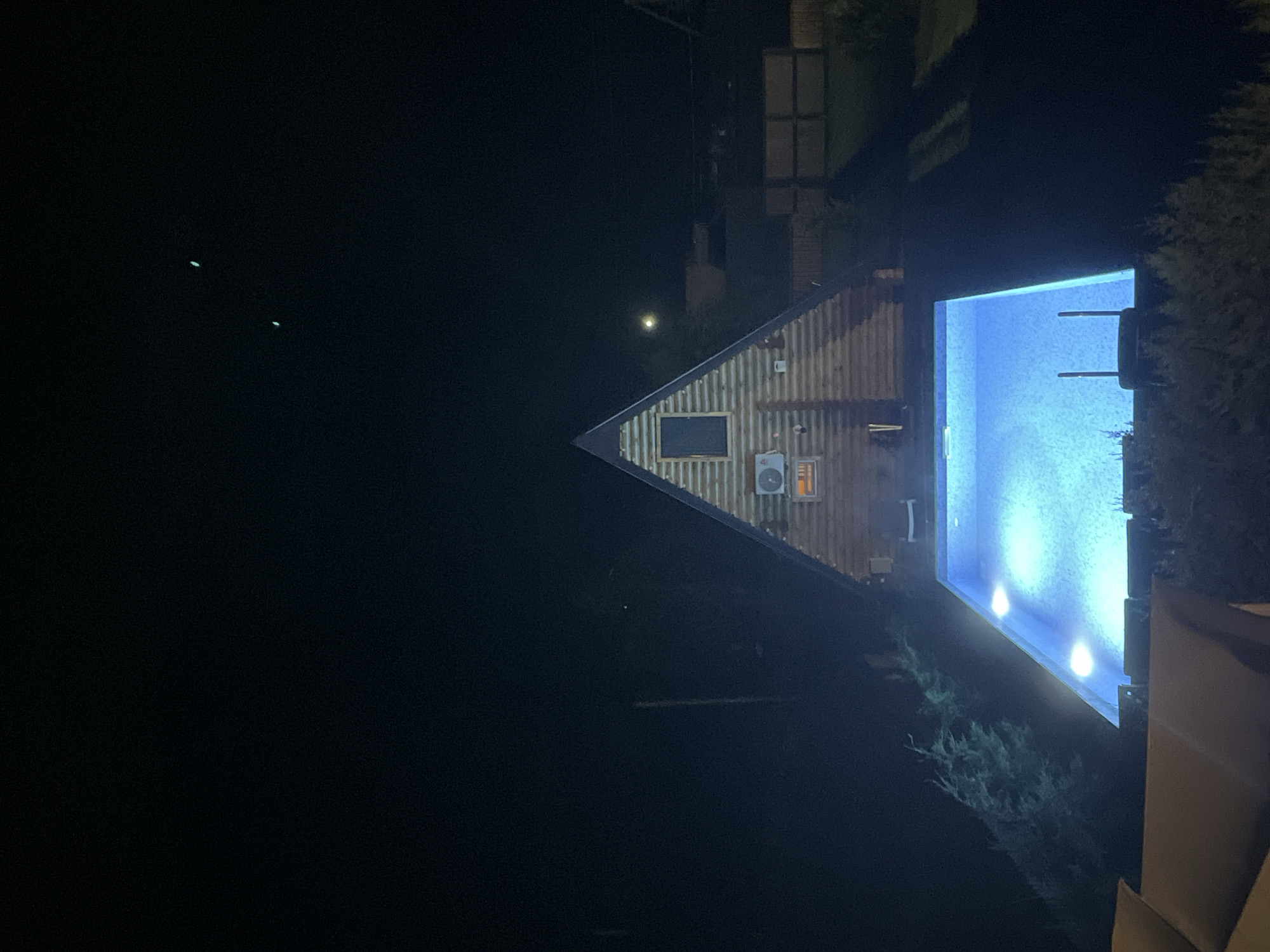 Triangular cabin glows at night beside a blue pool in Georgia